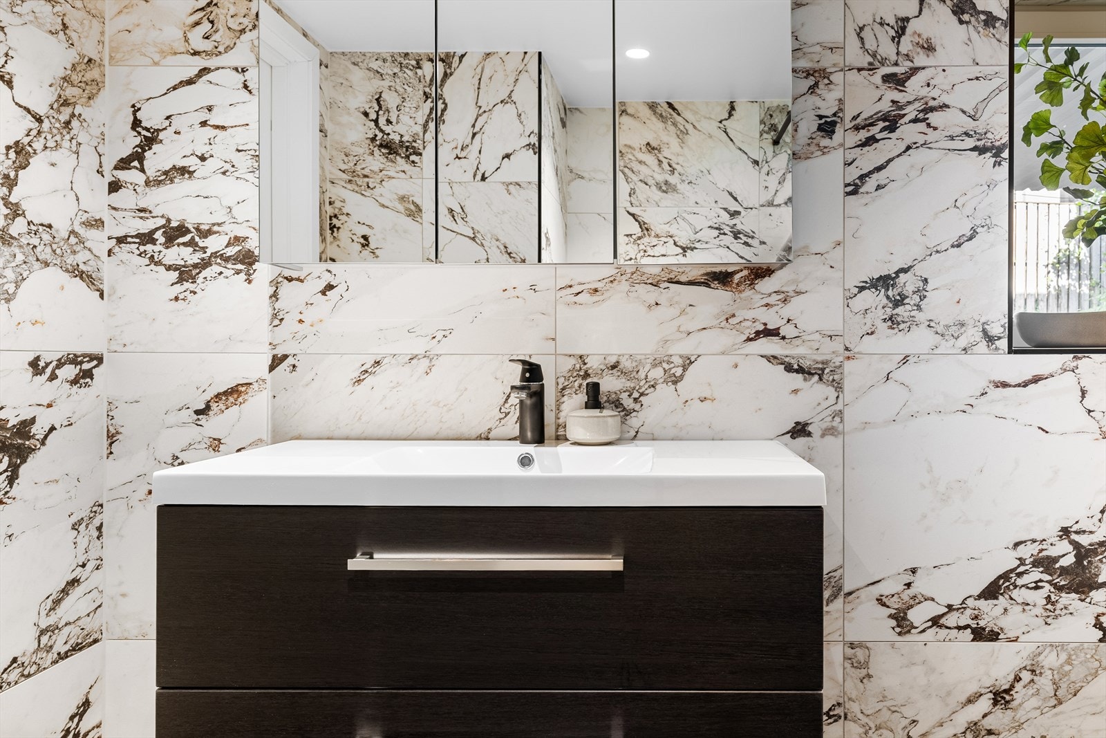 Badet er utstyrt med vegghengt toalett, helstøpt servant, skuffer under servant med slette fronter og dusjvegg i klart glass Galleribilde