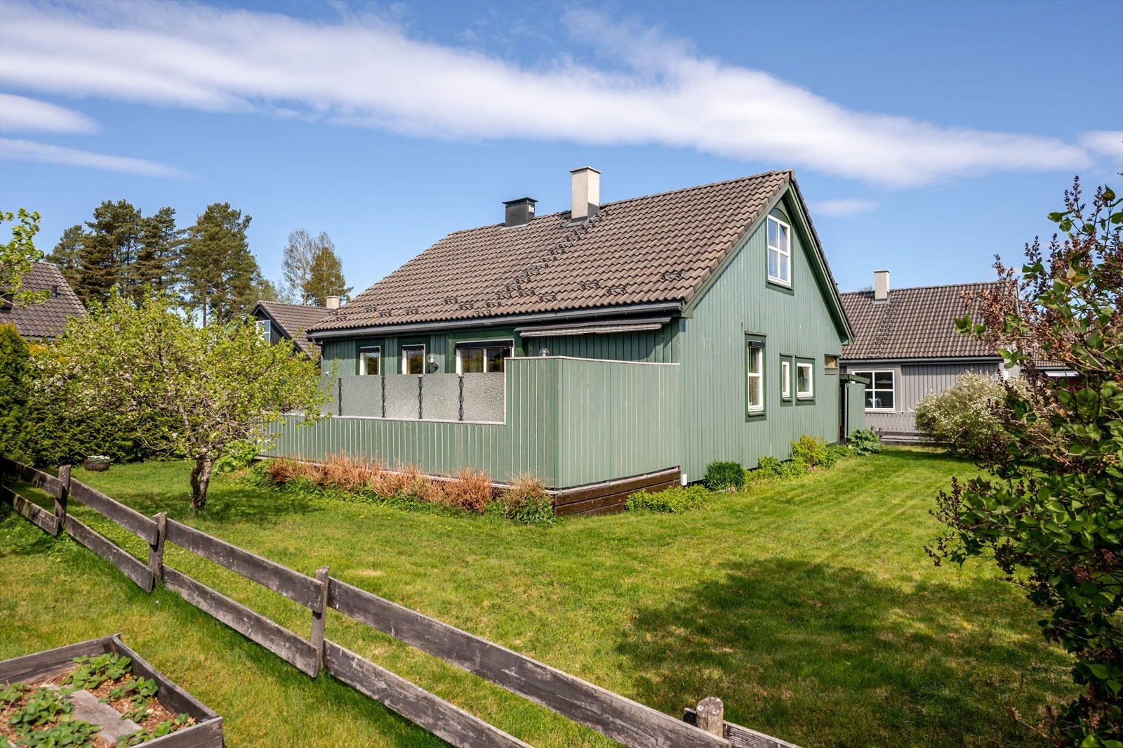 Koselig hage som er delvis innhegnet med gjerde og hekk. Ryddig og pent opparbeidet med gressplen og variert beplantning. Galleribilde