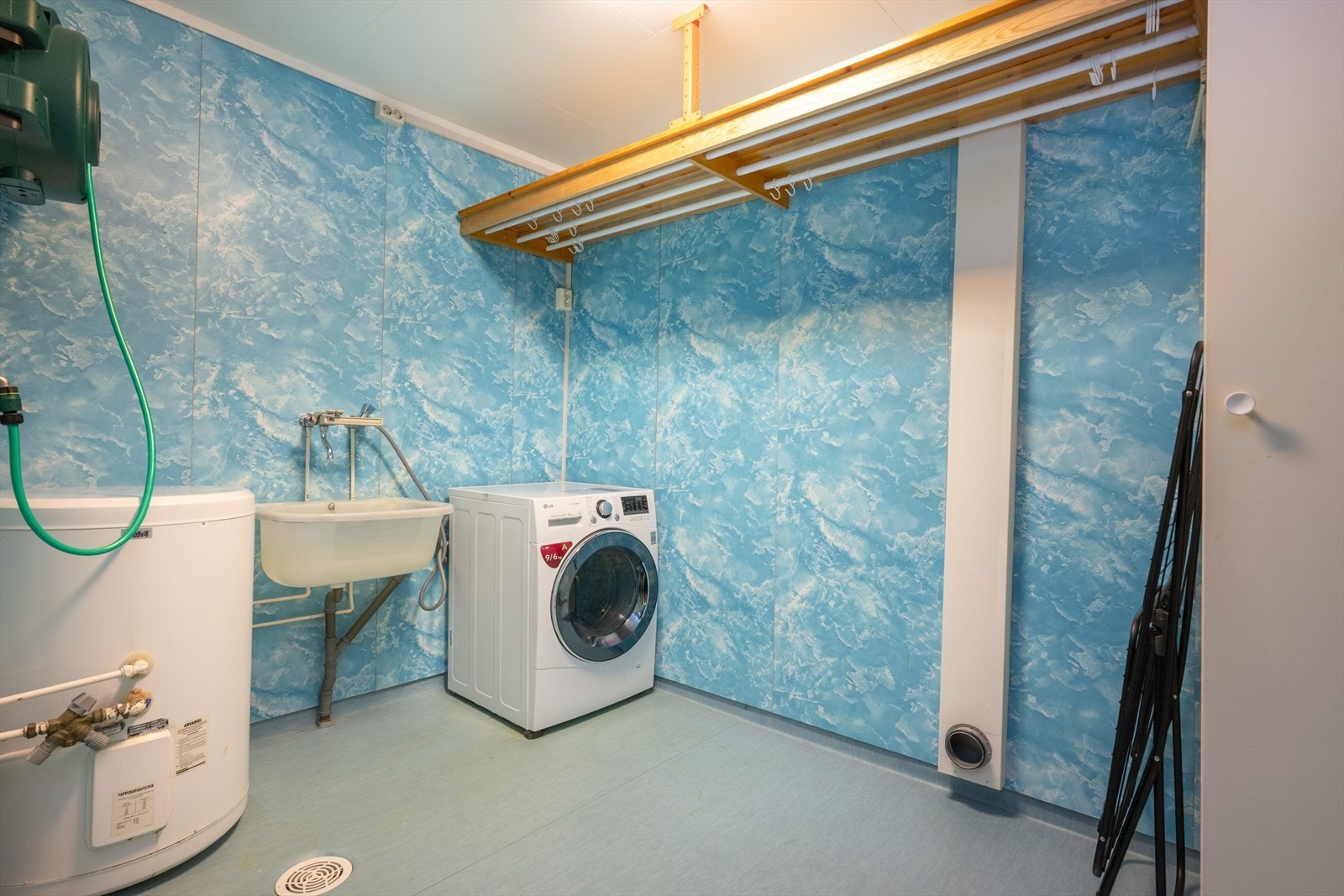 Vegg i vegg med badet er det et eldre vaskerom med vinylbelegg på gulv, baderomsplater på vegger og tak-ess plater i himling. Her er det vaskekum i pvc og opplegg for vaskemaskin. I tillegg er boligens varmtvannstank på ca. 120 liter plassert i rommet. Galleribilde