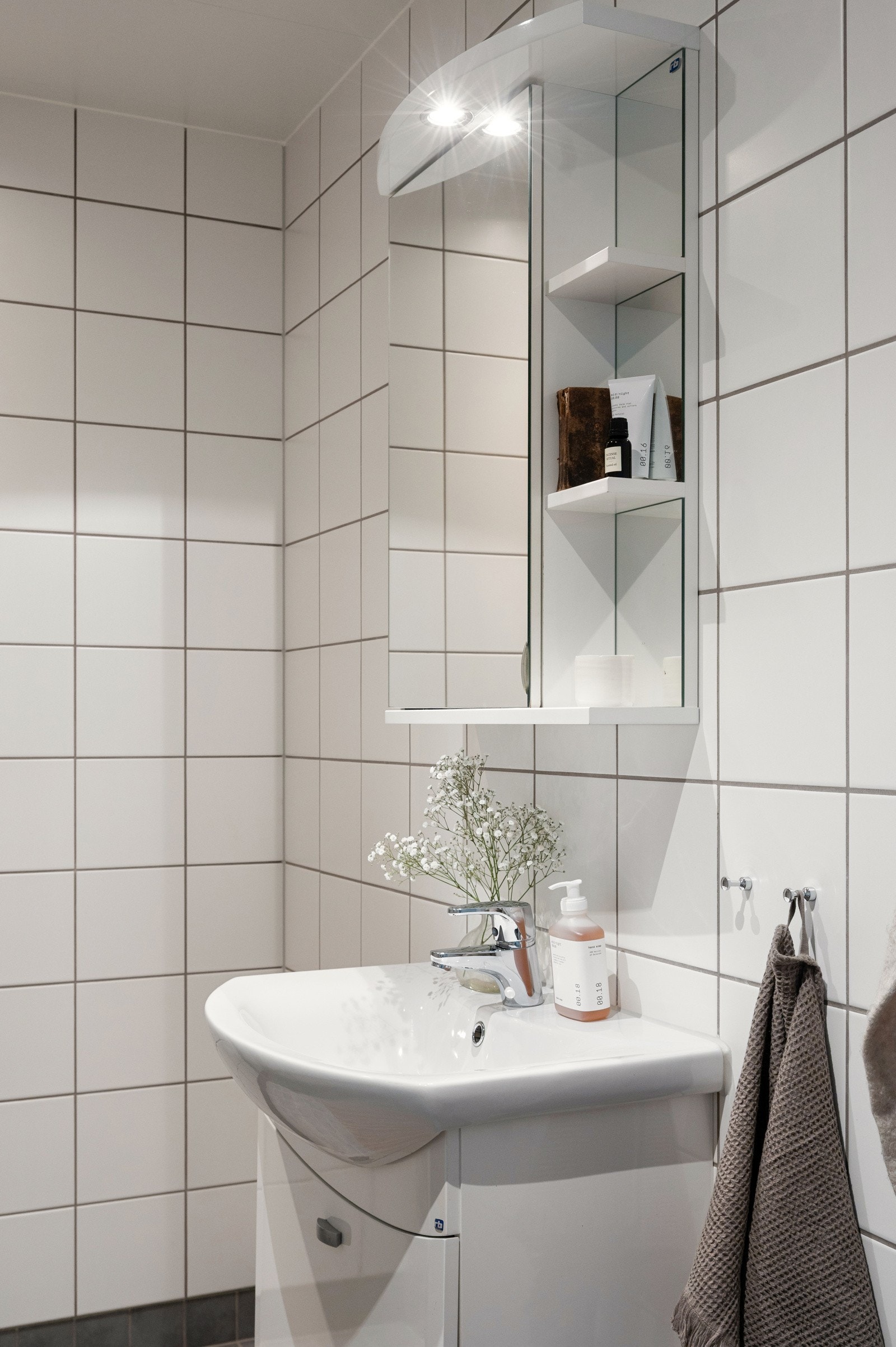 Badet er flislagt og har hvit servant med skapinnredning og speil med lys over. Galleribilde