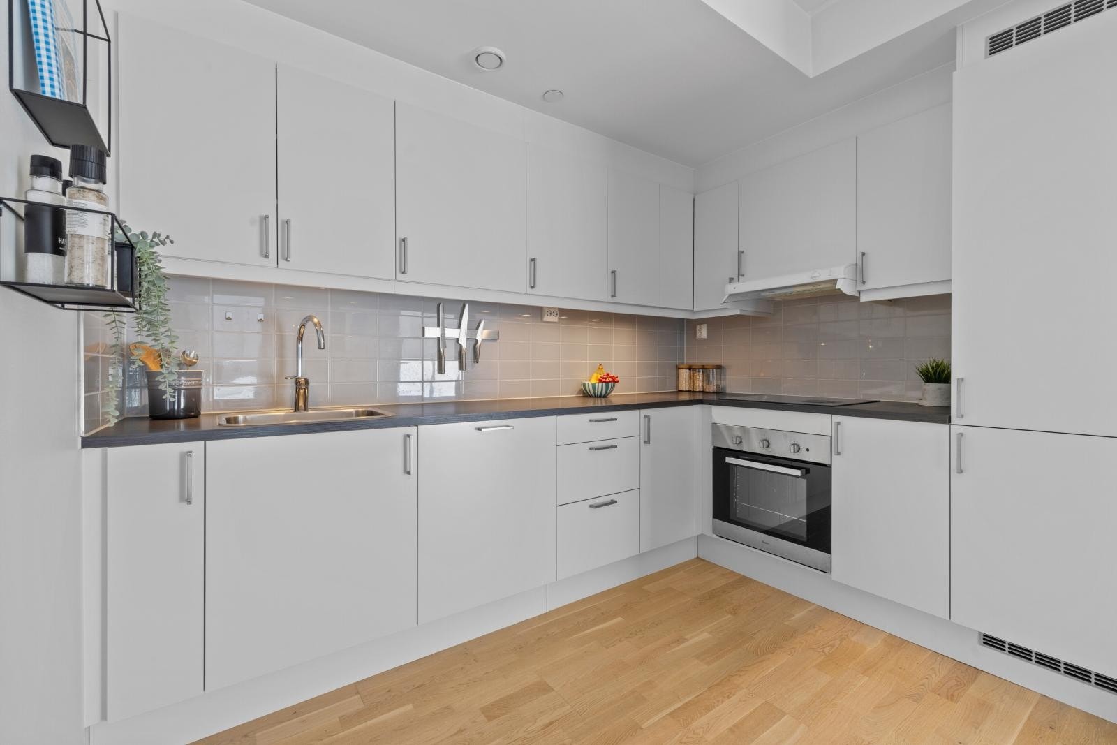 Kjøkkeninnredningen er moderne med hvite/glatte fronter, benkeplater i laminat og nedfelt oppvaskkum Galleribilde