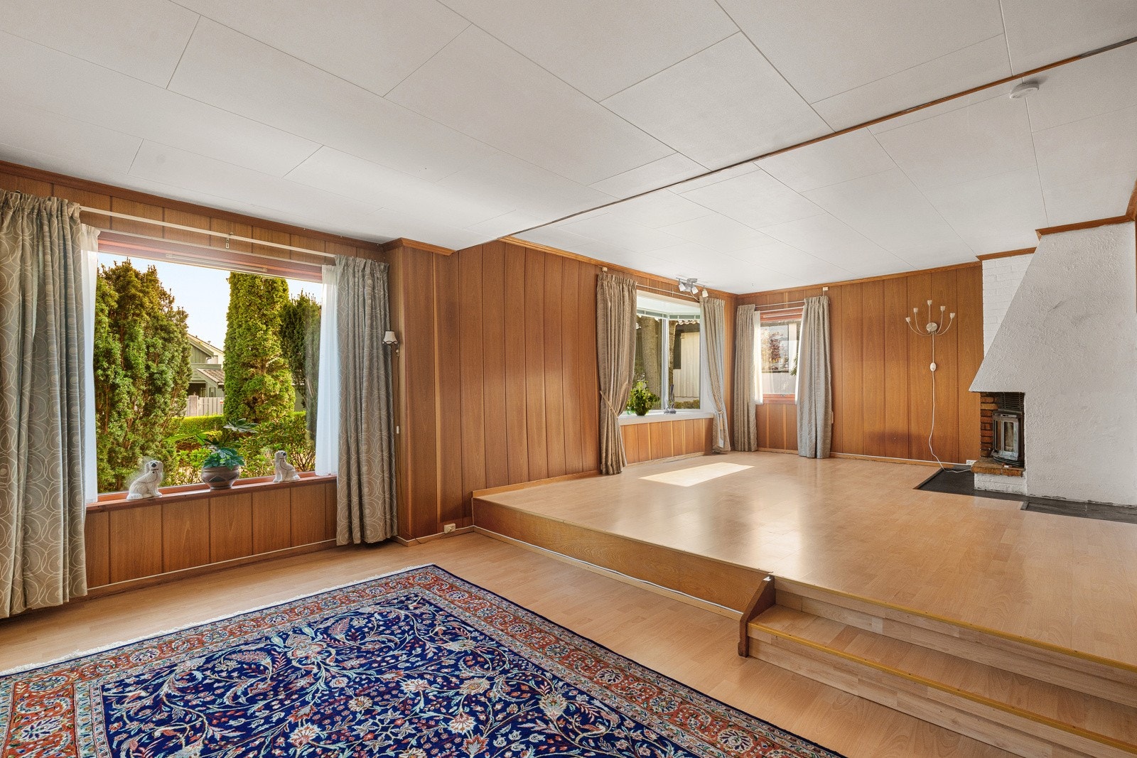 Her er det god plass, stor peis og flere vinduer som skaper en herlig atmosfære. Det er flere soner som gjør at man enkelt kan innrede med både salong, spisestue og tv-seksjon. Galleribilde
