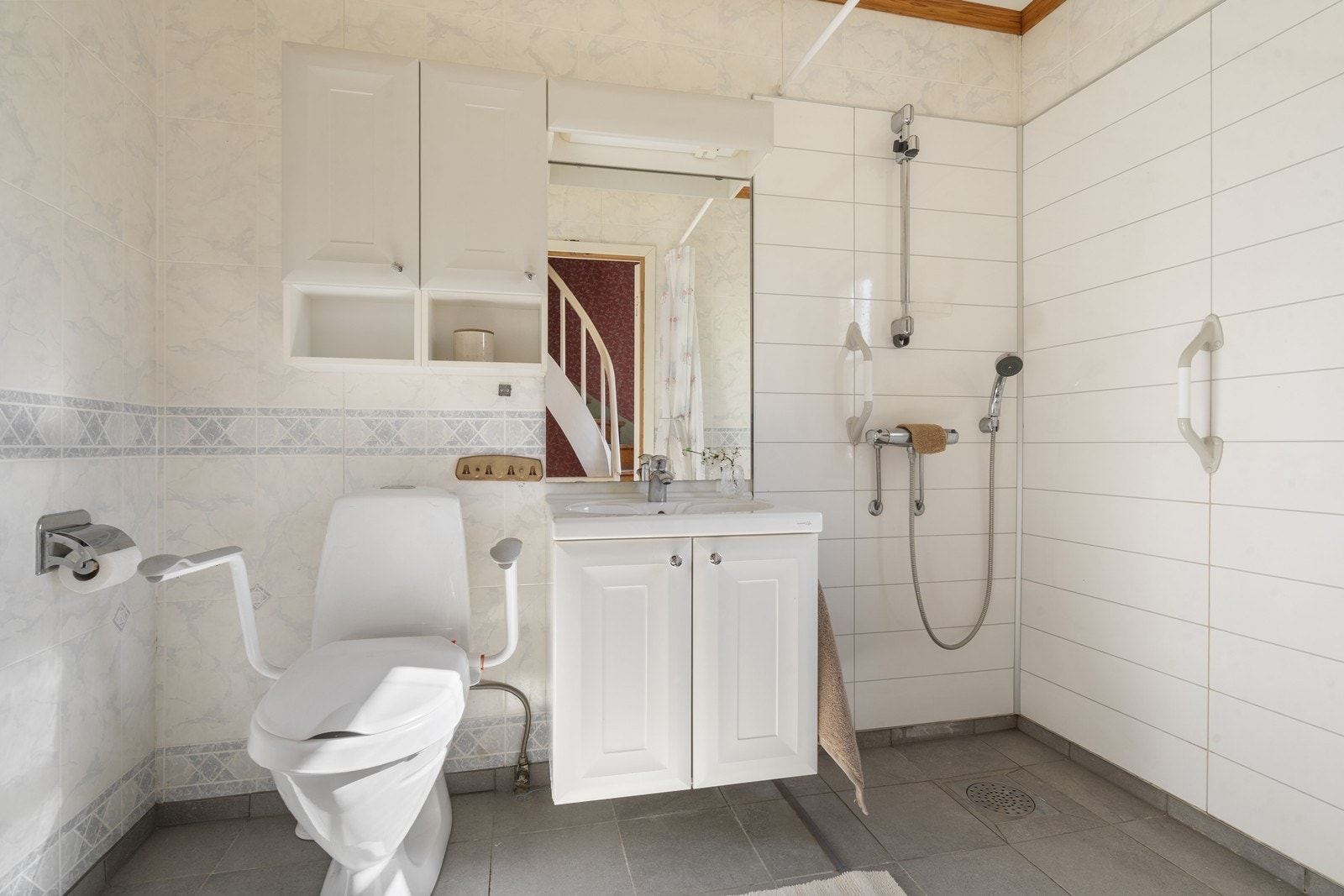 Lyst bad med baderomstapet og våtromsplater på veggene samt flislagt gulv med varmekabler Galleribilde