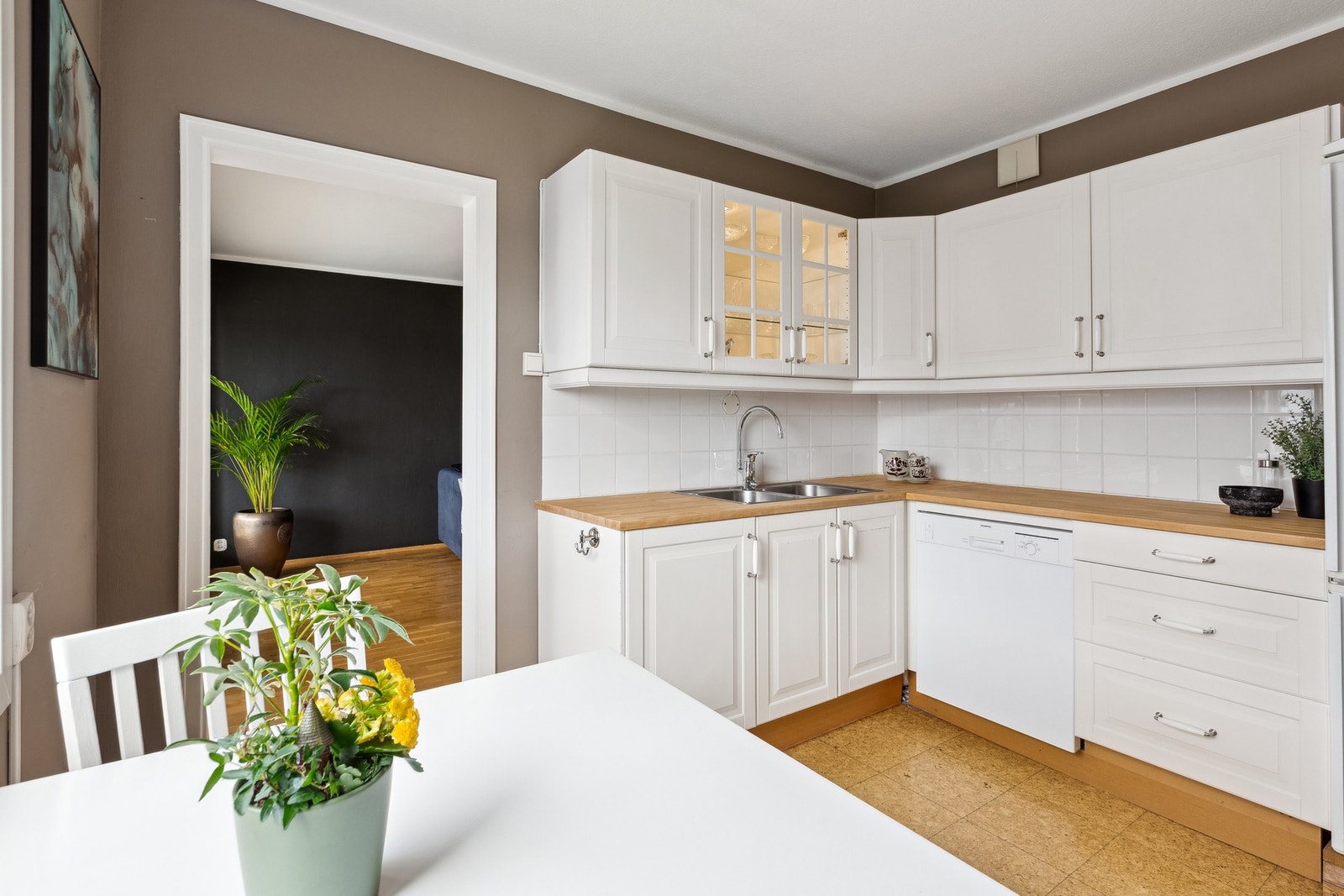 Kjøkken med lyse fronter og trebenk i varm kontrast. Galleribilde