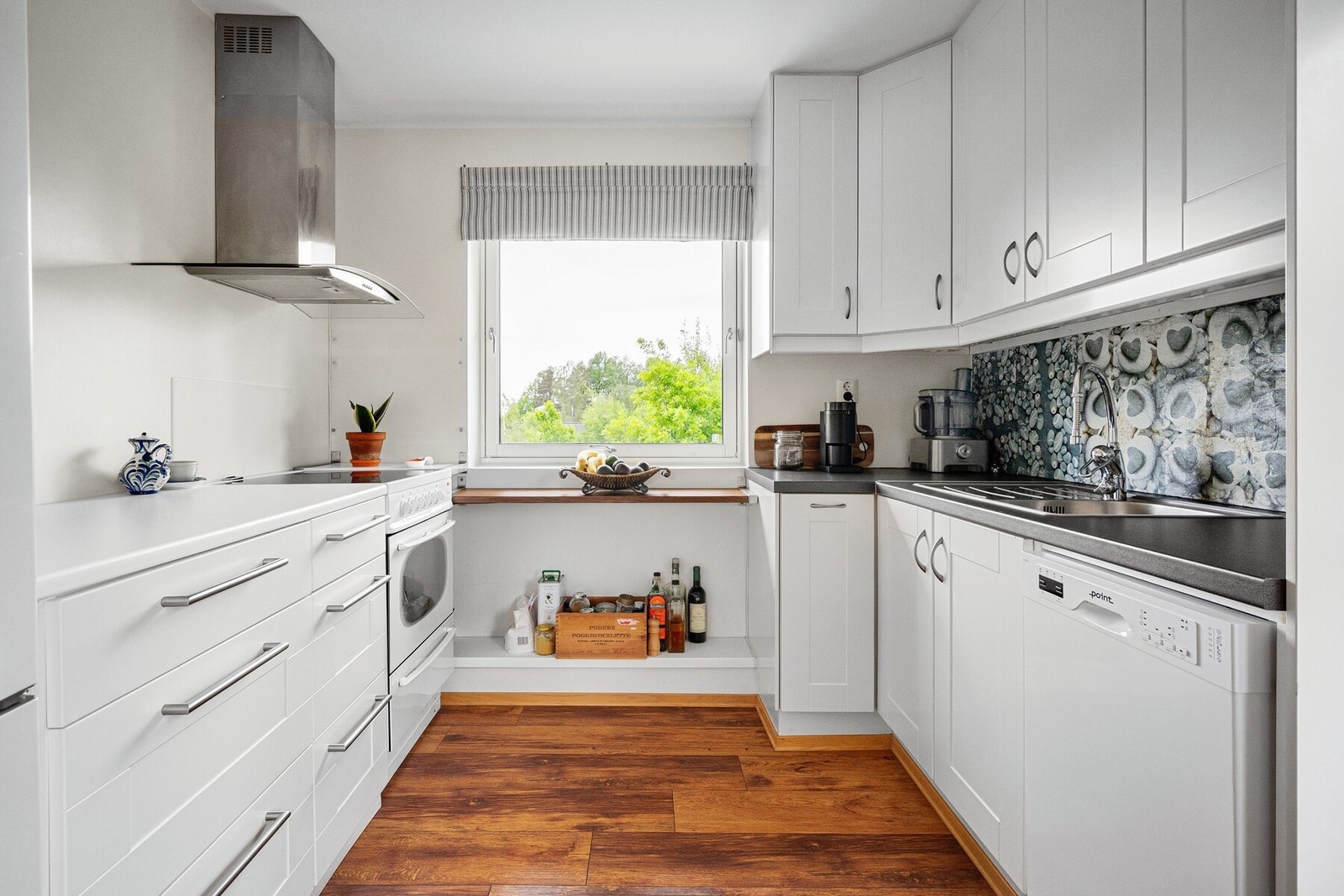 Et velutstyrt kjøkken i åpen løsning med stue, med plass til spisebord og hvitevarer. Galleribilde