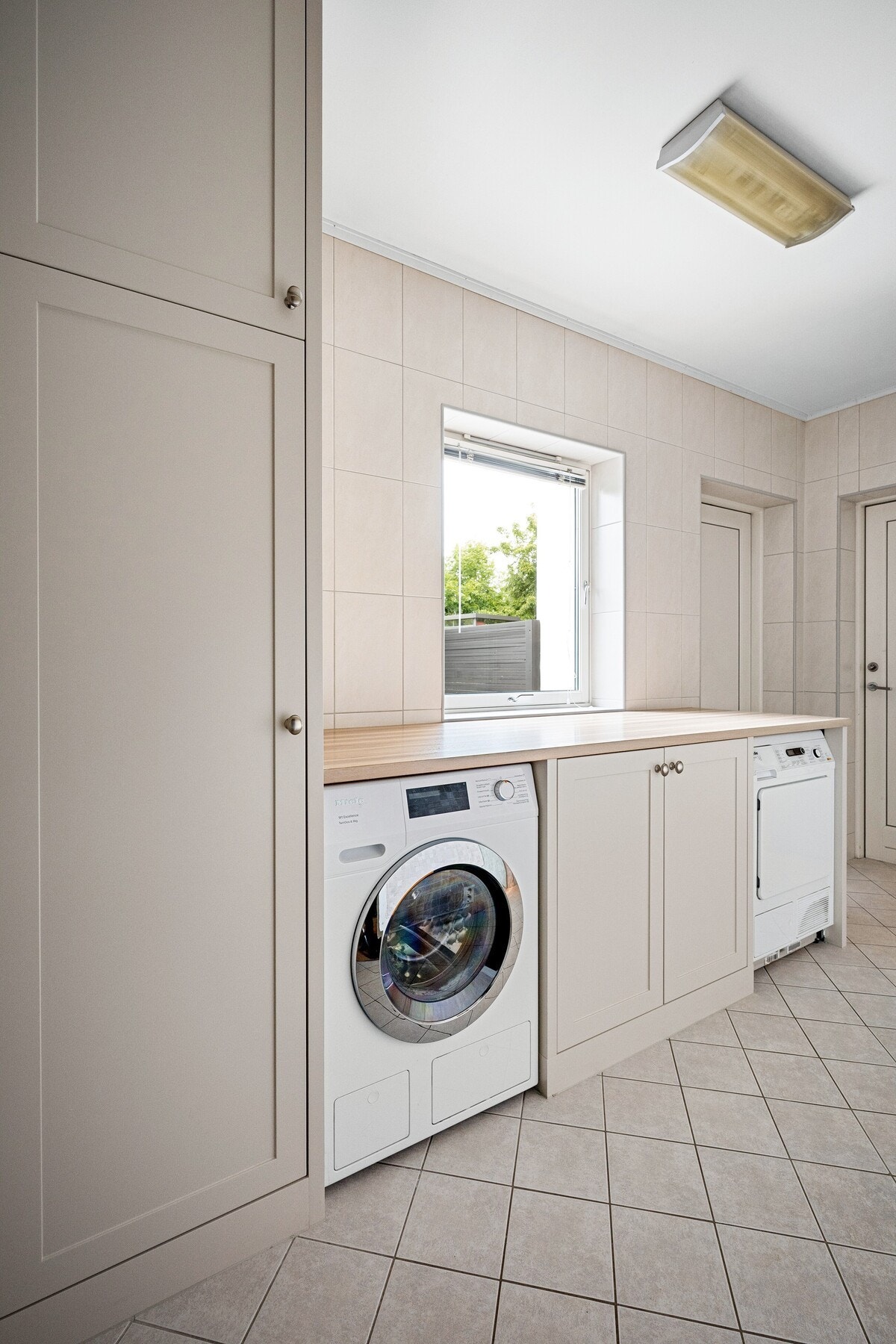 Et funksjonelt vaskerom med egen dusjsone og praktisk adkomst til både terrassen og integrert garasje. Galleribilde