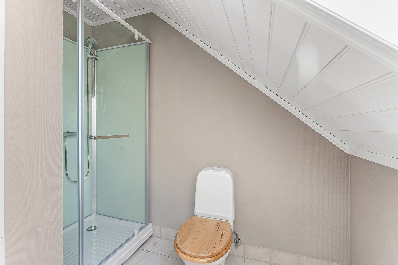 Badet er utstyrt med en enkel vask, et gulvstående toalett, og frittstående dusjkabinett. Galleribilde