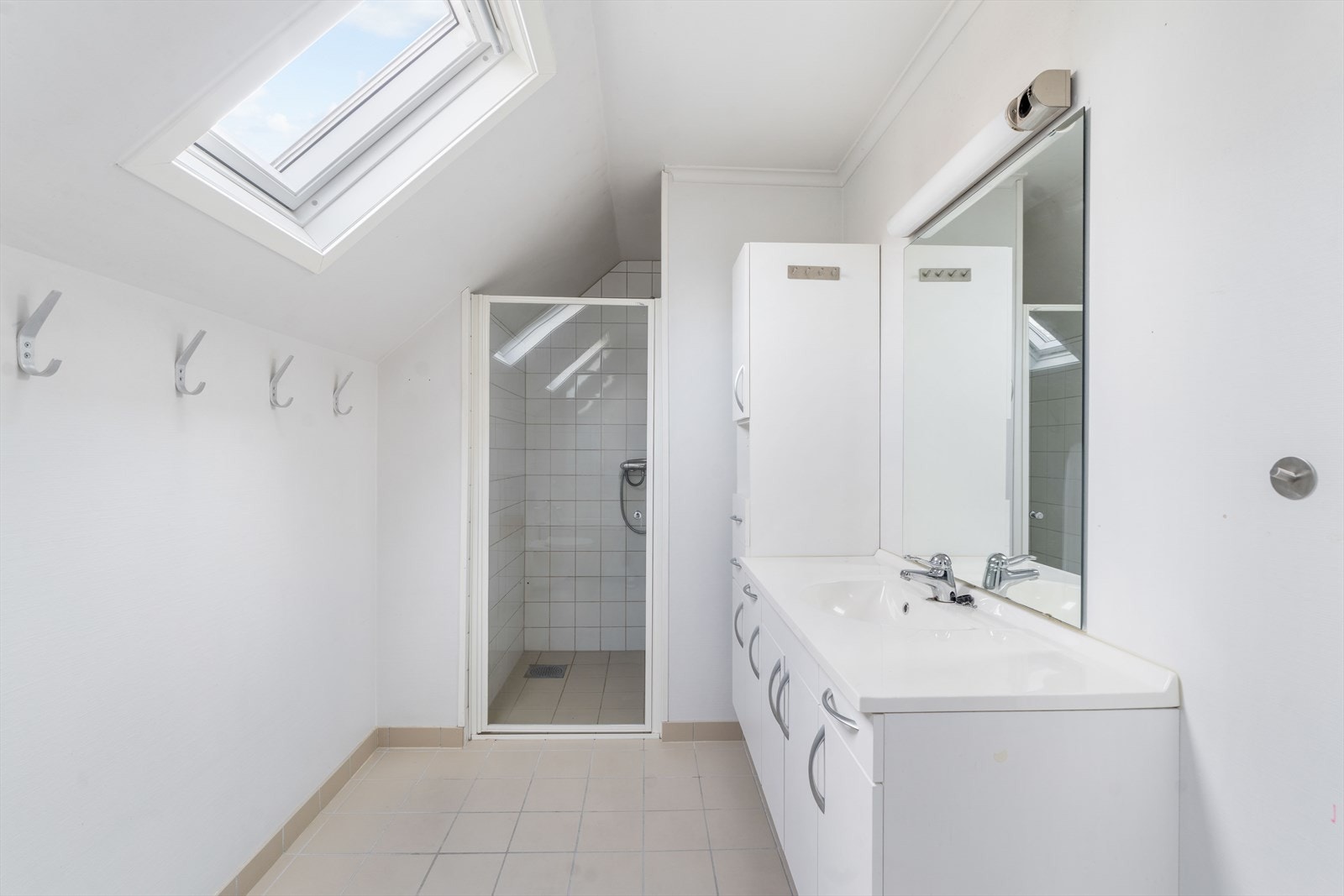 Bad med fliser på gulv og i dusjsone. Hvit baderomsinnreding, dusj og badekar. Galleribilde