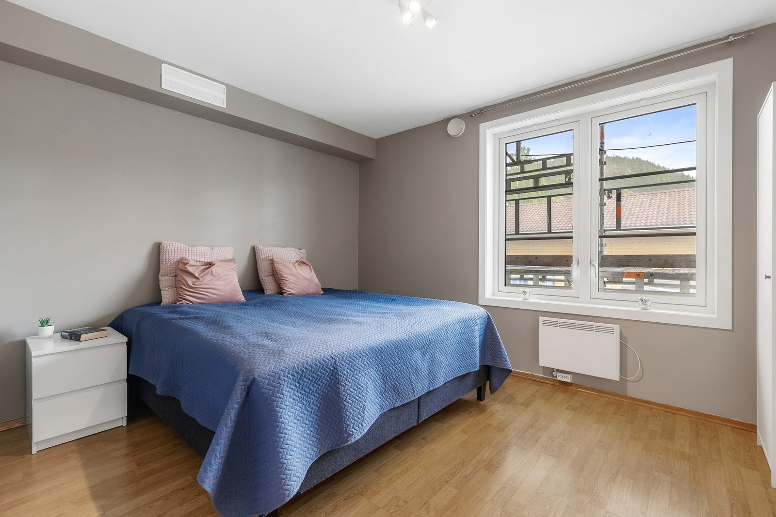 Lyst og romslig soverom med laminat på gulv og slette vegger malt i en nøytral beige tone Galleribilde