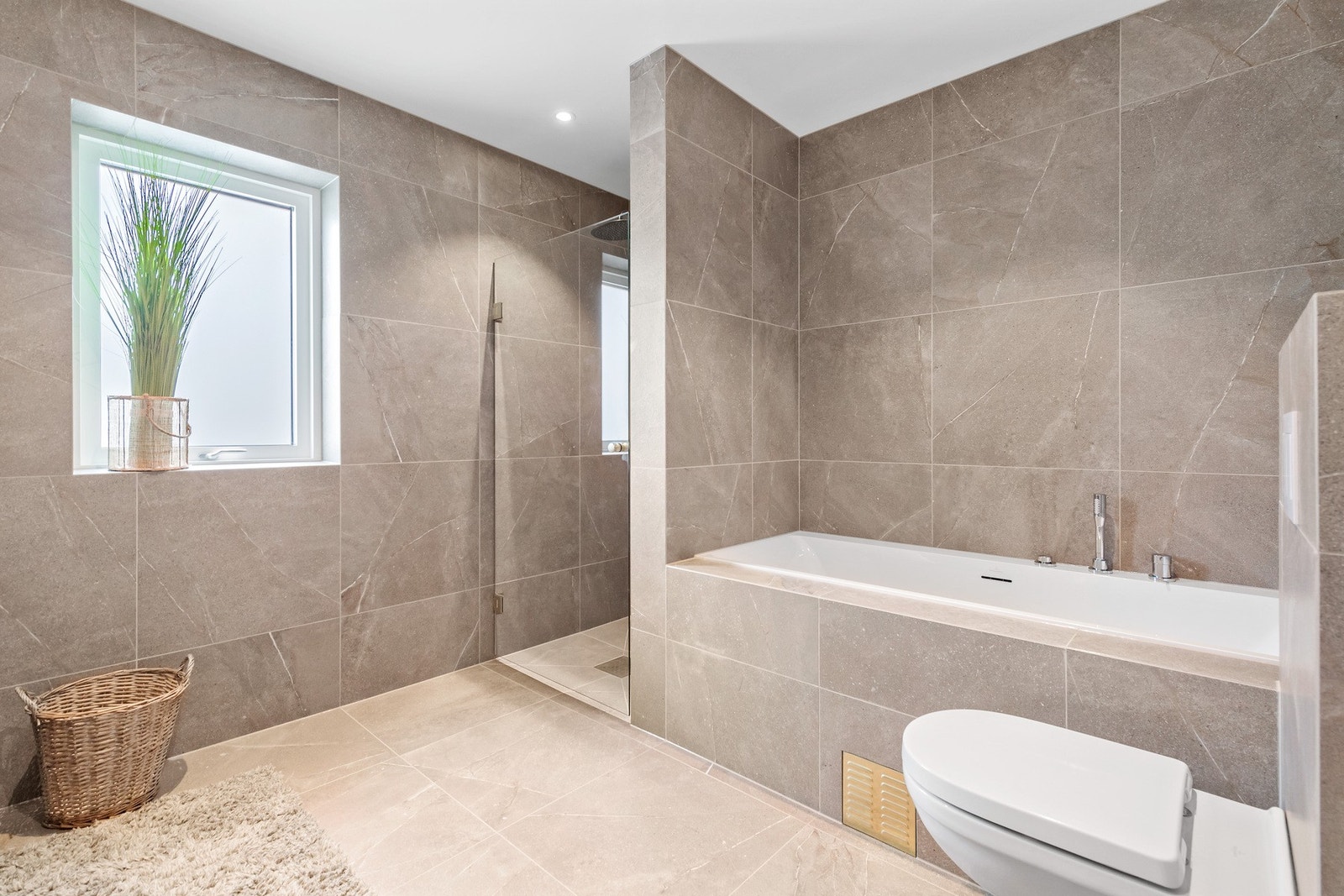 Lekkert, flislagt bad med badekar og dusjnisje. Galleribilde