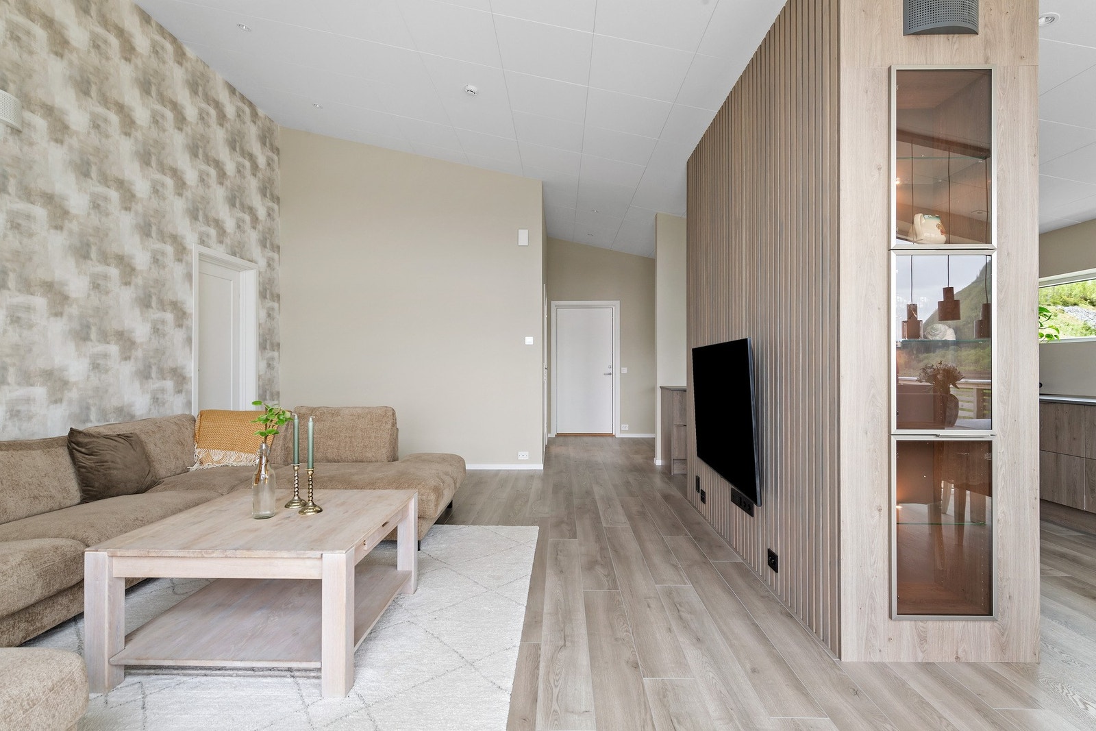 Veggen mellom kjøkken og stue fungerer som en fin romdeler. Legg merke til det innfelte vitrineskapet i veggen. Galleribilde