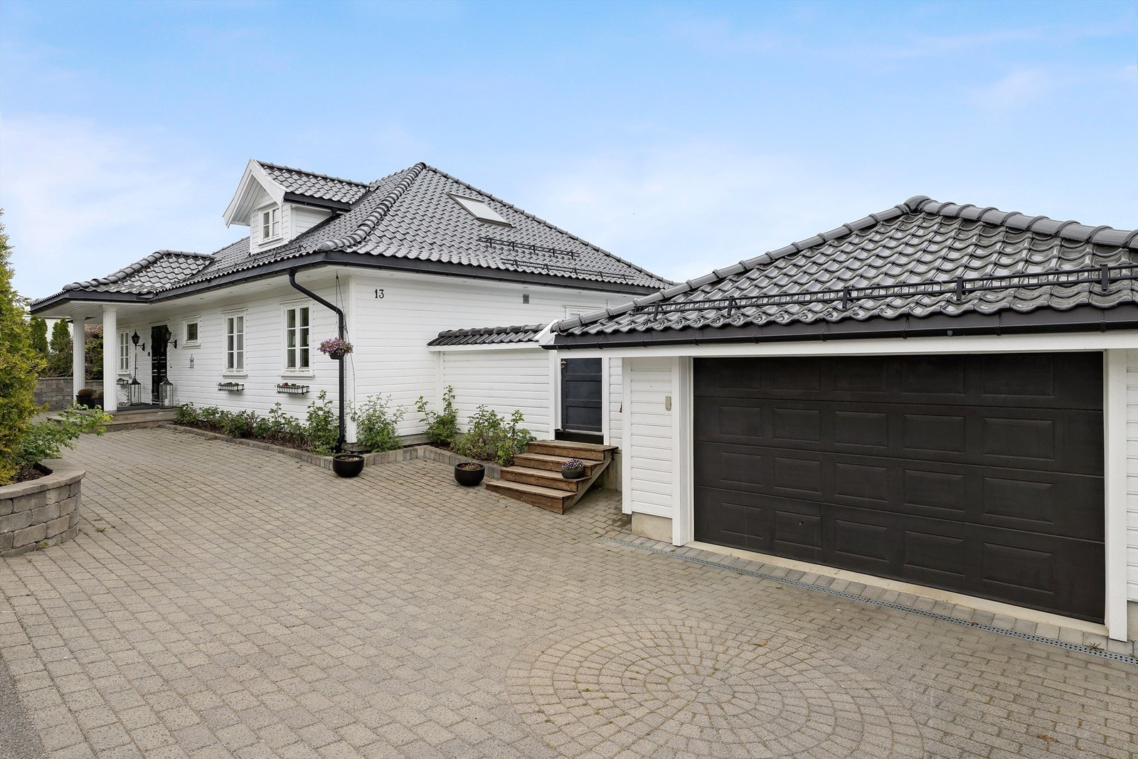 Stor gårdsplass med belegningsstein. Garasje. Galleribilde