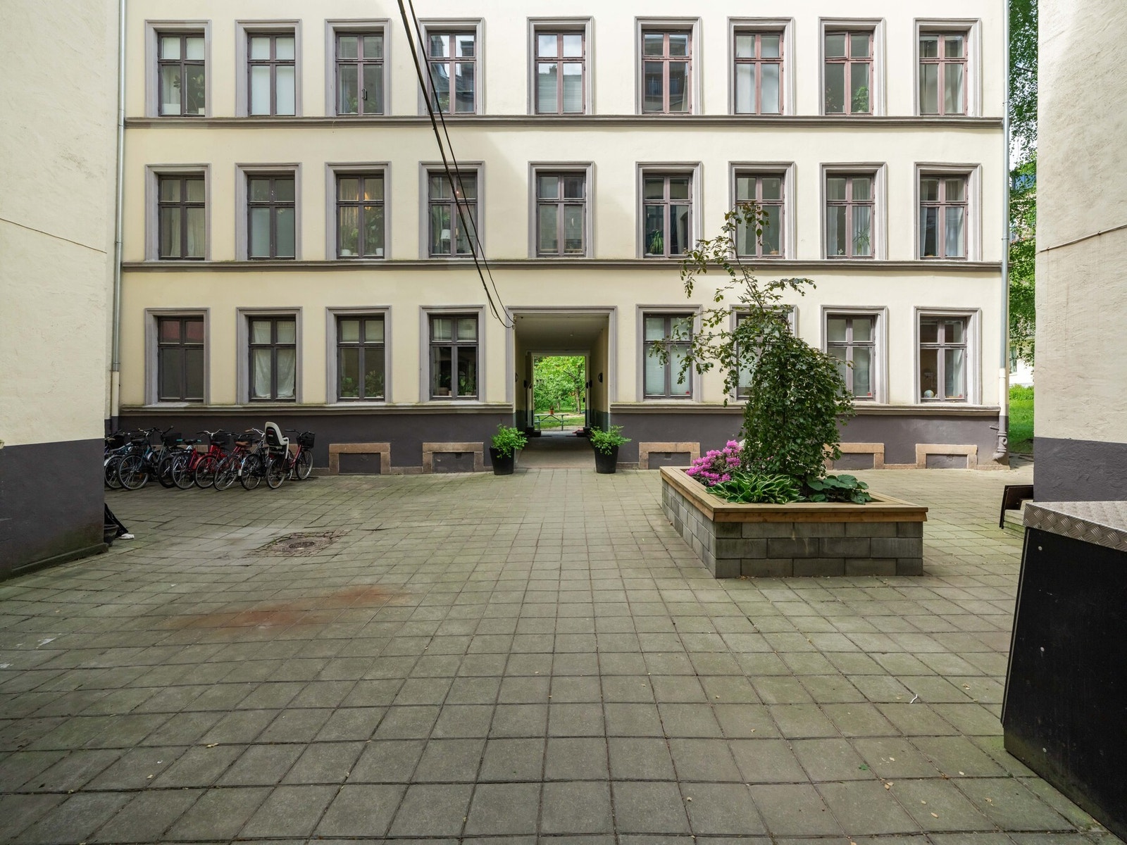 Gårdsrommet er opparbeidet og skjermet med betongheller, enkel beplantning og sykkelstativ. Galleribilde