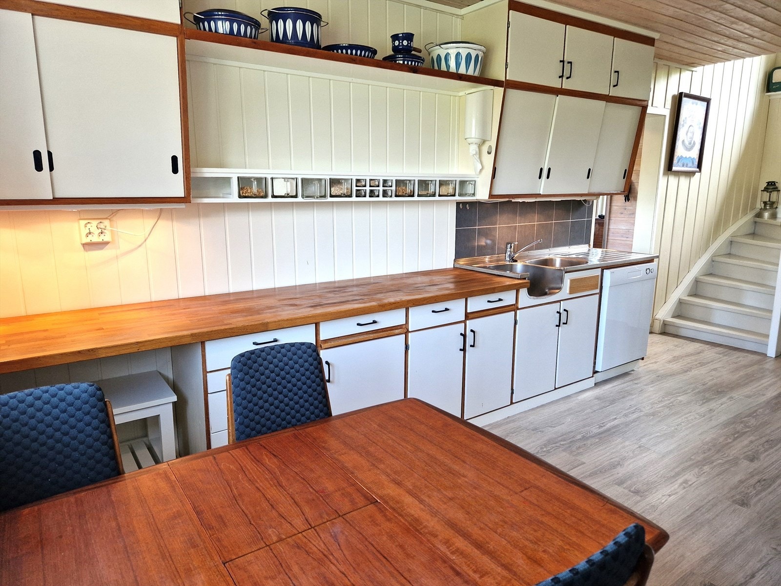 Rundt hjørnet i stua er kjøkkenet plassert. Nostalgisk innredning med et hint av moderne innslag. Benkeplate i heltre og delikate fliser på brannmur som virkelig står i stil med resten av boligen. Galleribilde