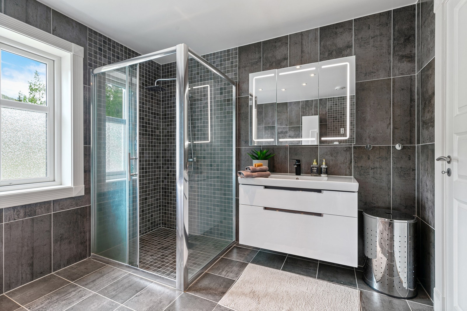 Badet har gulvvarme, downlights, heldekkende servant og speilskap med integrert belysning. Galleribilde