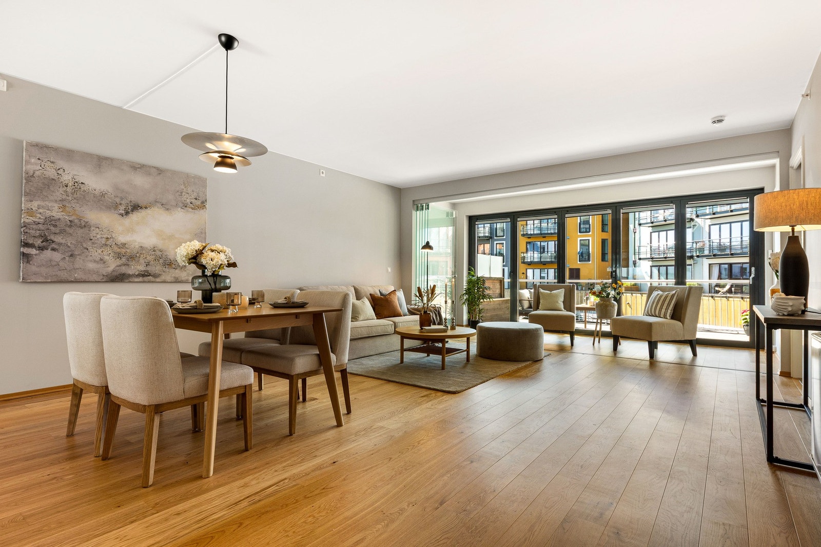 Lys og romslig stue- og spisestueområde med store vinduer som gir rikelig med naturlig lys. Moderne gulv og nøytrale farger skaper en innbydende atmosfære. Utgang til Solrom og terrasse. Galleribilde