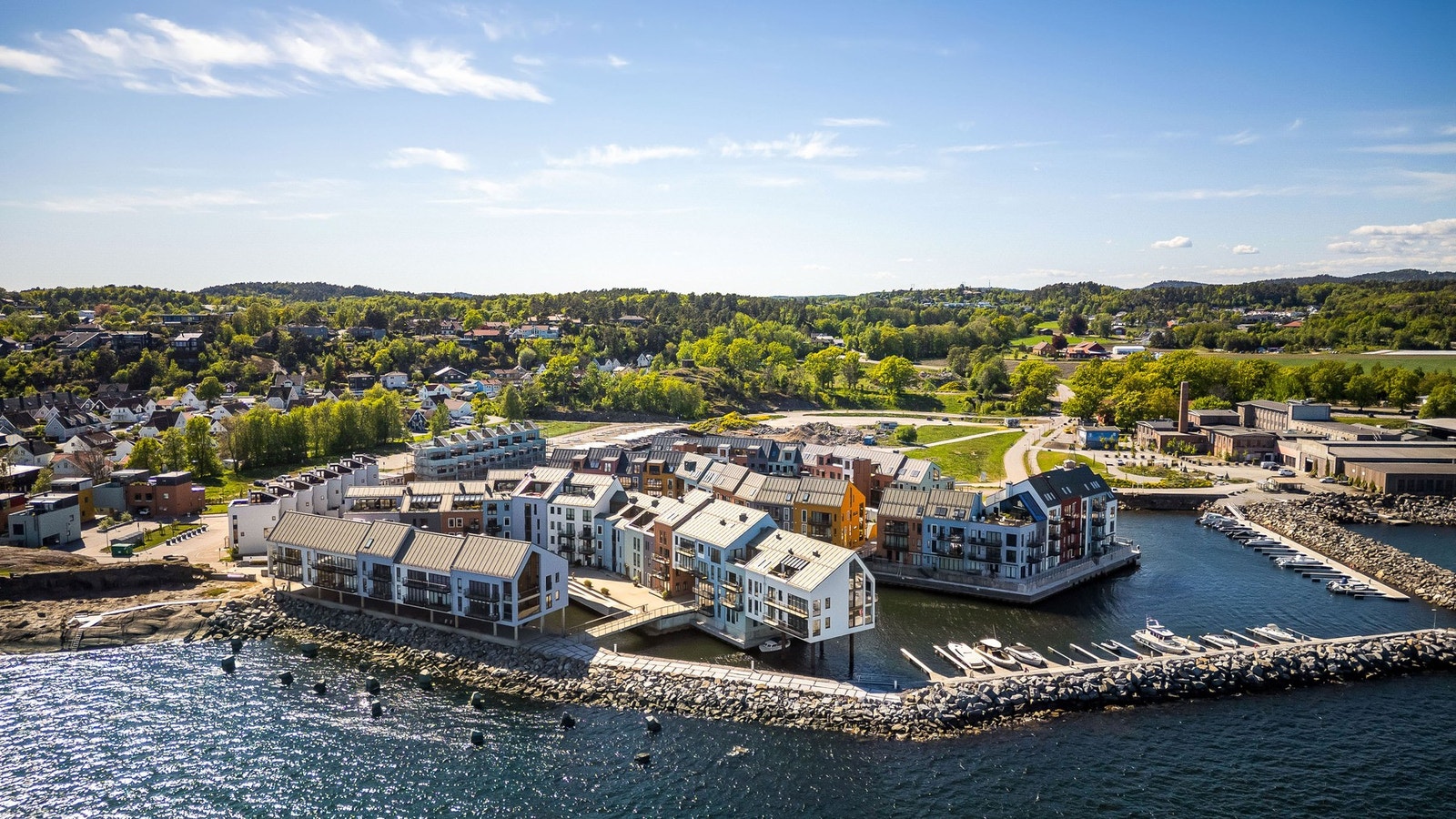 Området består av flere bygninger med varierte fasader omgitt av sjøen og natur. Galleribilde