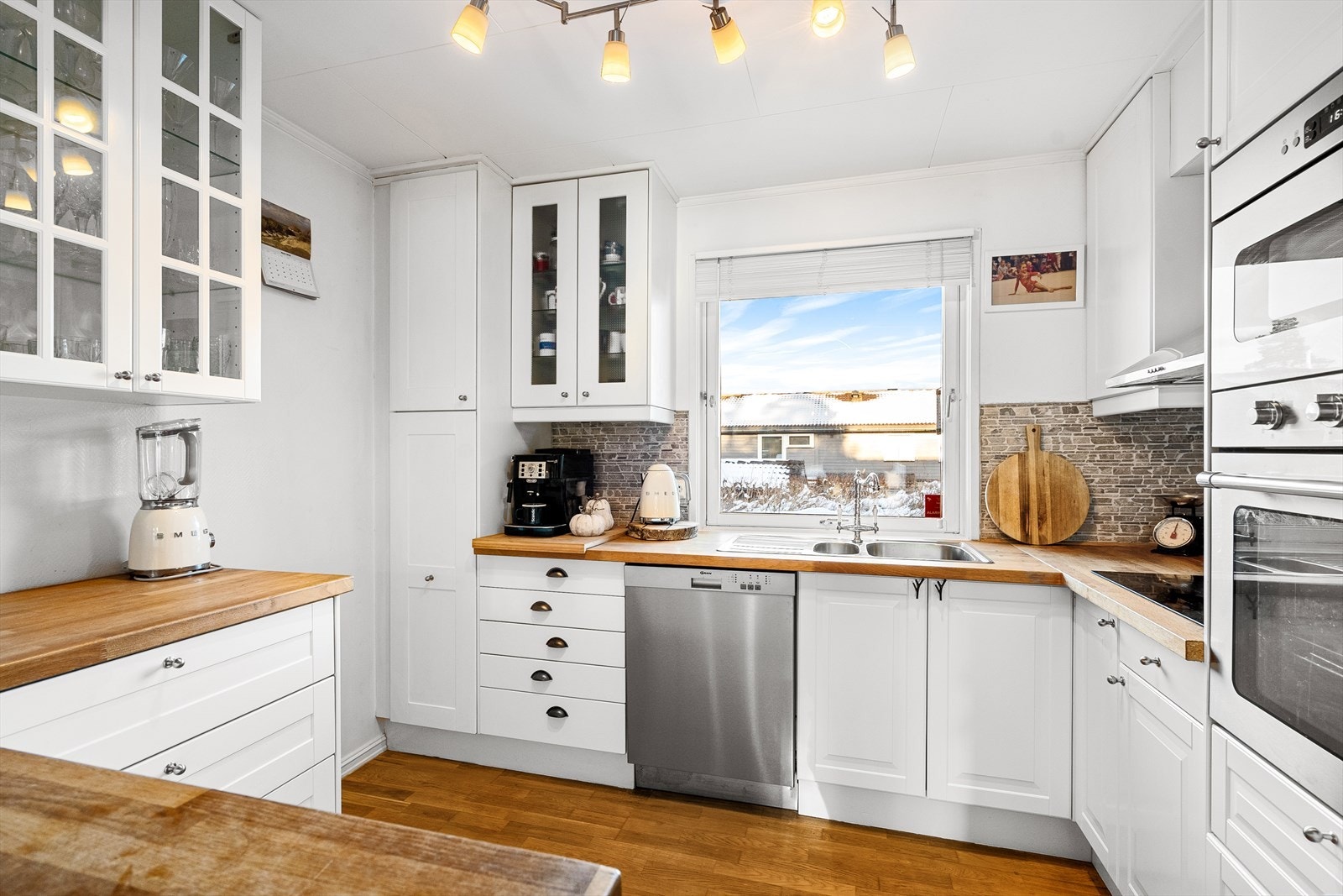 Klassisk og stilrent kjøkken med hvite, profilerte fronter og heltre benkeplate Galleribilde