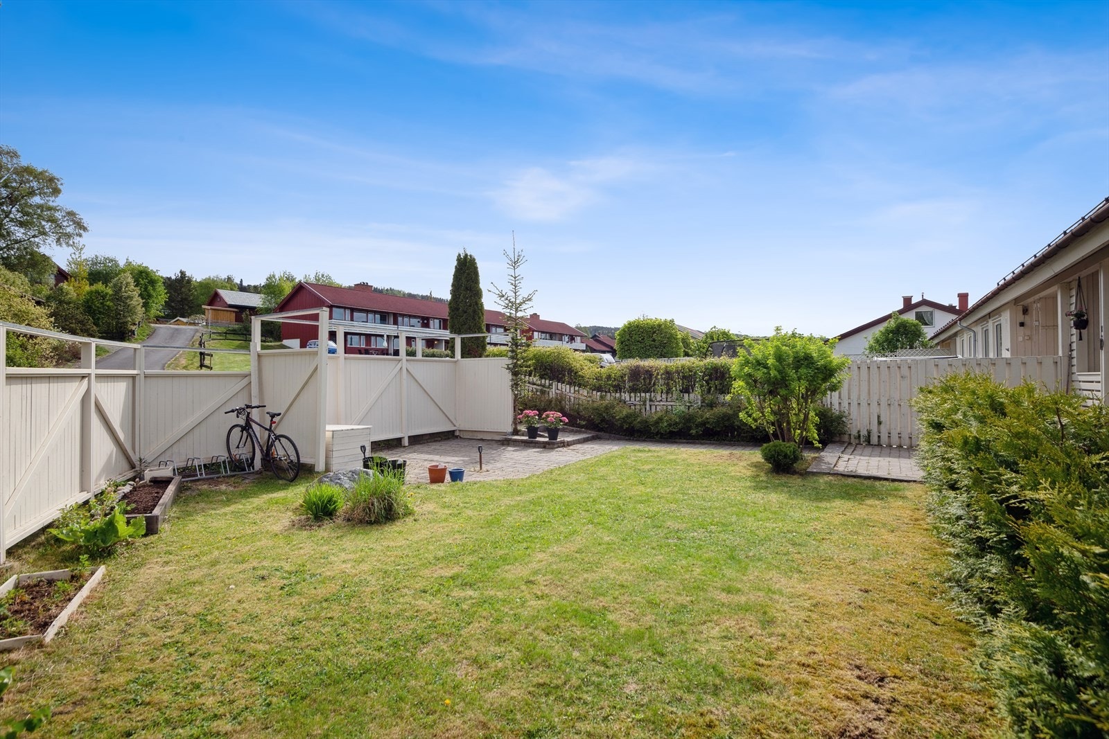 Pent opparbeidet hage med plen, belegningsstein, prydbukser og diverse beplantning. Galleribilde