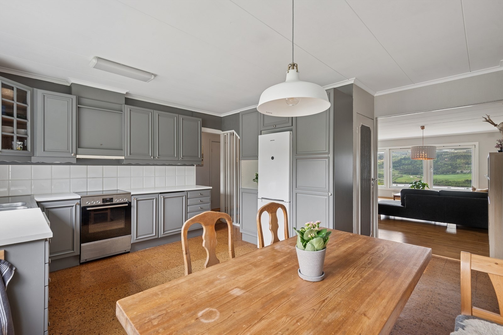 Innredningen har profilerte, heltre fronter og en lys laminert benkeplate med dobbel kjøkkenkum. Over kjøkkenbenken er det fliser og det er belysning under overskapene. Galleribilde