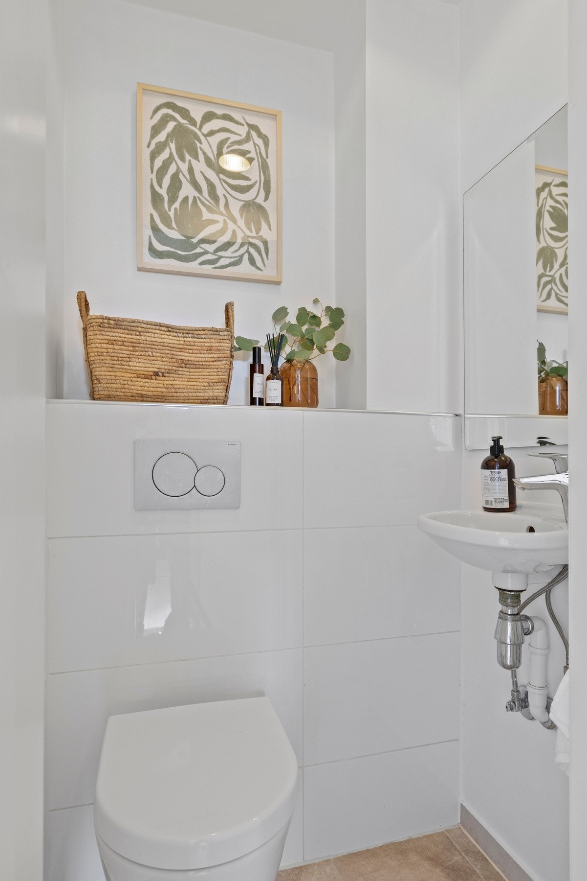 Toalettrommet har flislagt gulv og glatte, malte veggflater. Det er veggmontert toalett samt et seravnt og speil. Galleribilde