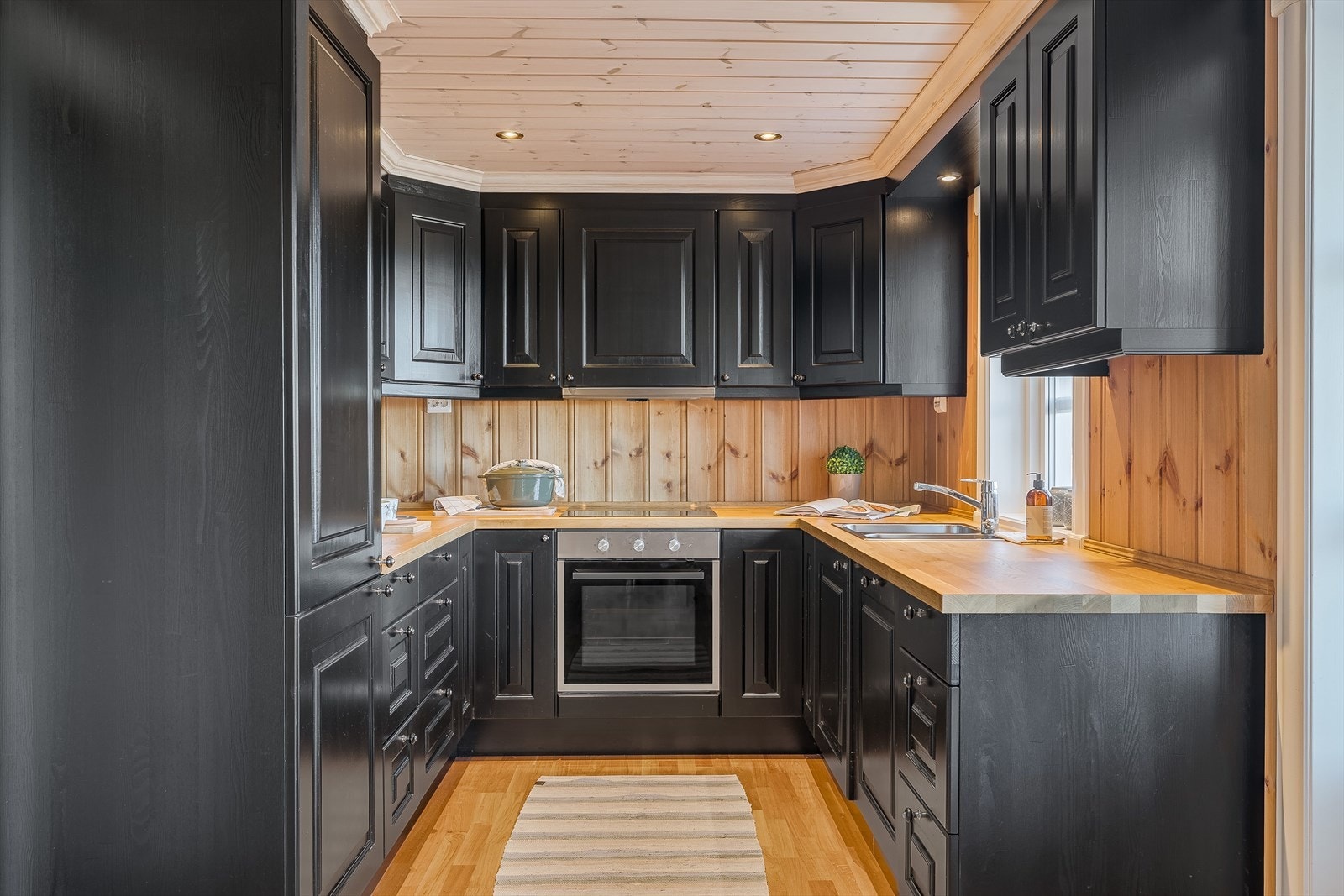 Kjøkkenet har en pen, heltre innredning med takhøye overskap, finert benkeplate og integrerte hvitevarer som koketopp, stekeovn, oppvaskmaskin og kjøl-/fryseskap som medfølger. Galleribilde