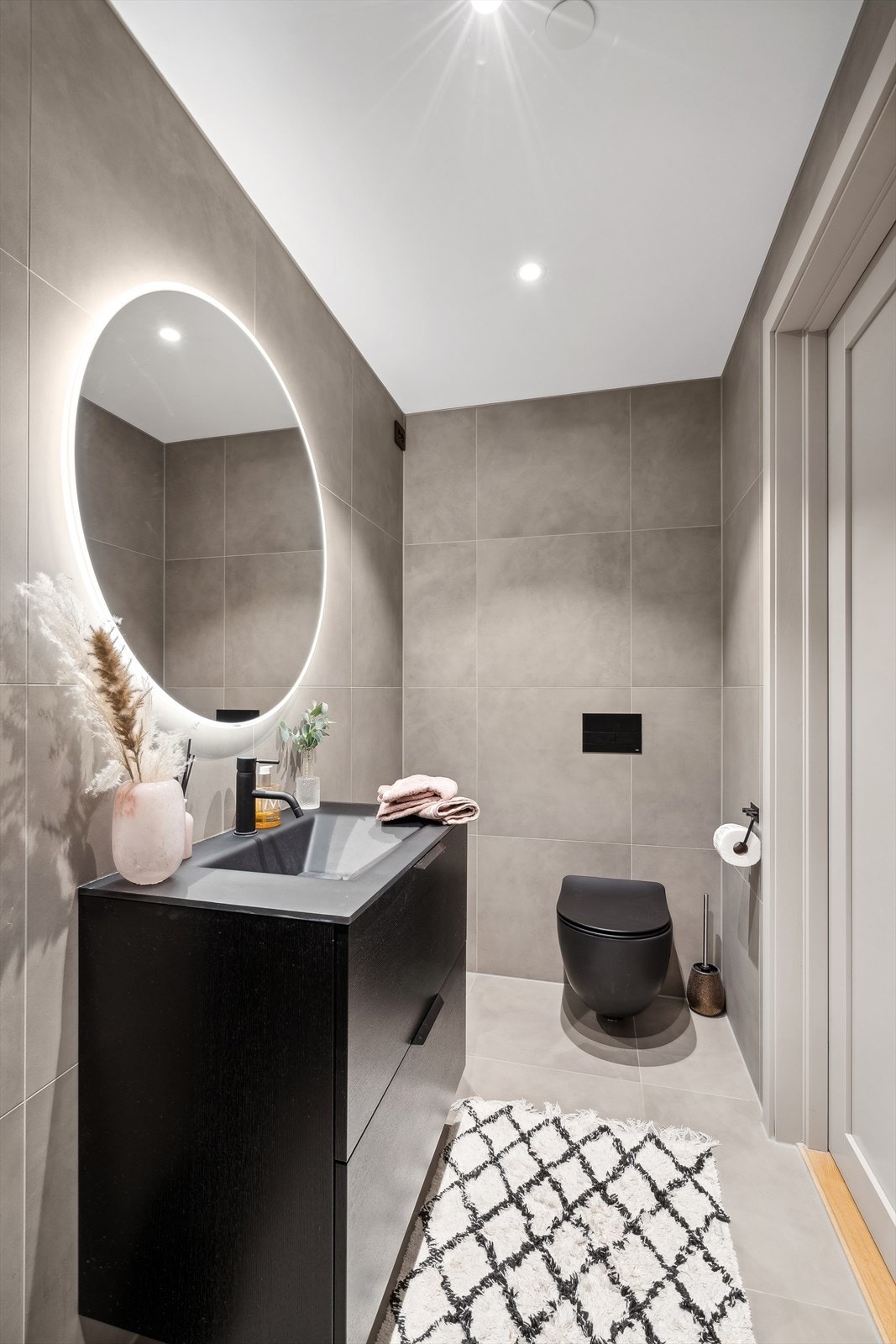 Badet har stor dusjnisje med glassvegg og regnfallsdusjhode, servant med skapinnredning, samt vegghengt toalett. Drensåpning fra vegginnbygget toalettsisterne ført til vegg i dusj. Galleribilde