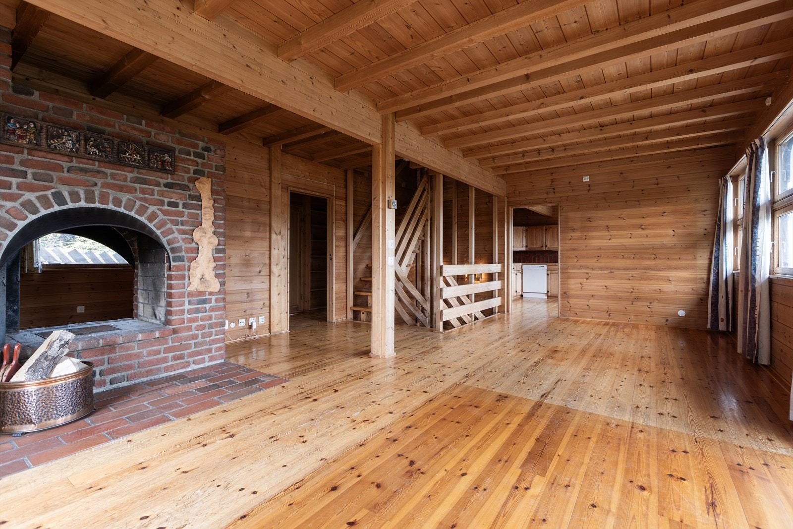 Sentralt i stuen er det en teglstenspeis som varmer godt på kalde dager. Galleribilde