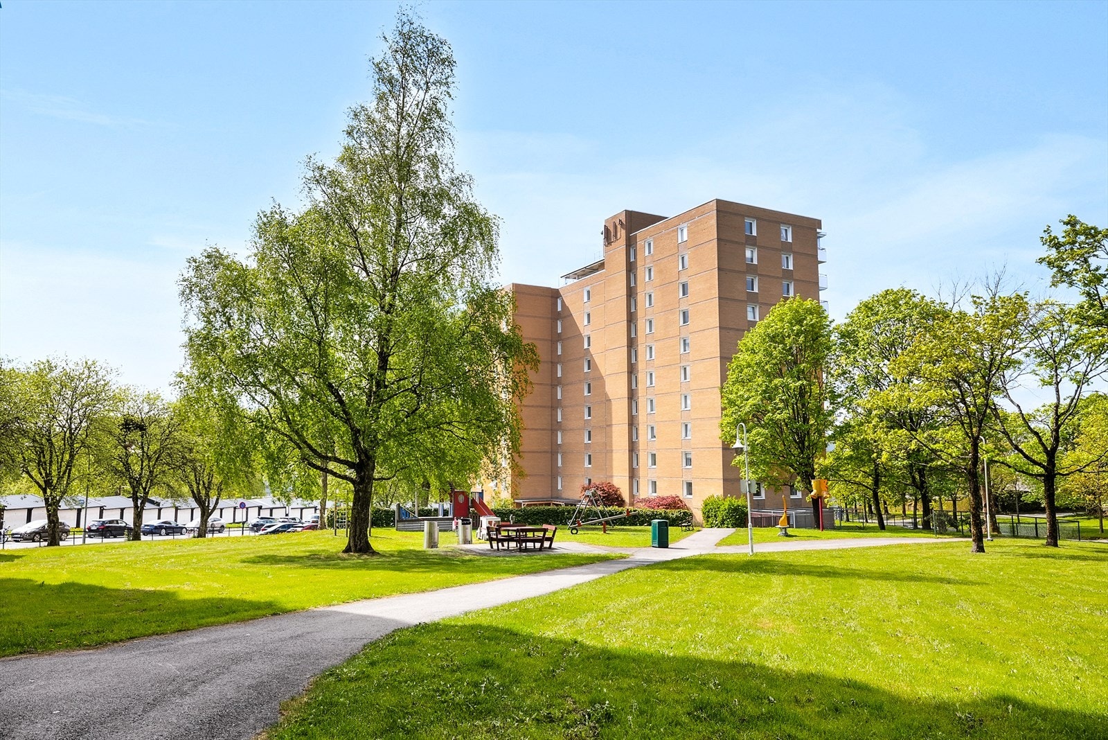 Velholdt boligblokk omgitt av grøntarealer og sitteplasser. Galleribilde