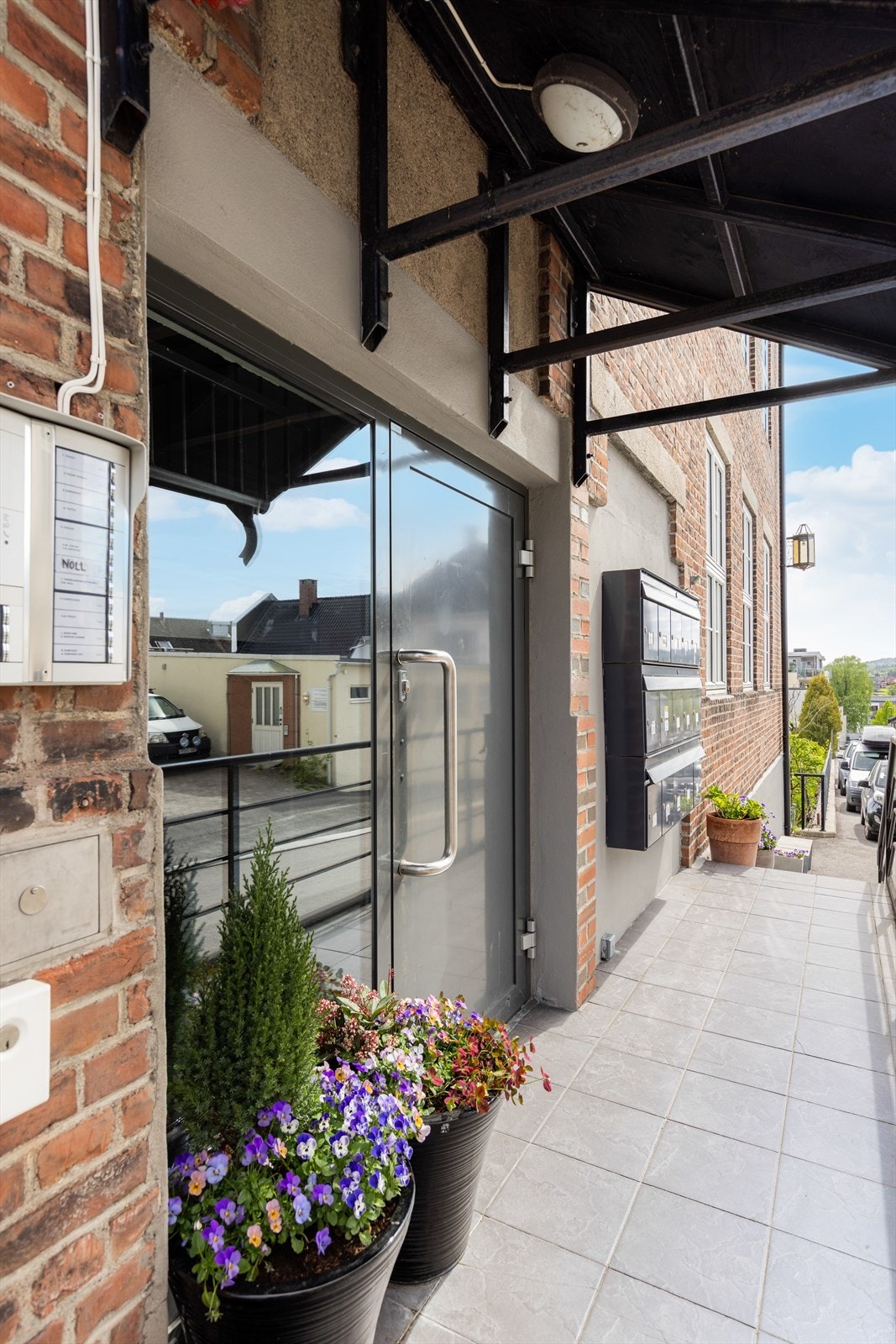 Inngangsparti på gateplan med trapp og rullestolrampe inn til felles gangareal med heis. Galleribilde