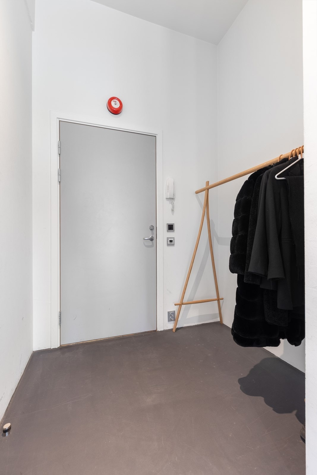 Med adkomst fra felles inngangsparti kommer man inn i gangen hvor det er lagt sementbasert Weber designgulv som gir videre inn i stua og kjøkkenet og gir et helhetlig uttrykk. Det er montert dørtelefon for enkelt å kunne slippe besøkende inn. Galleribilde