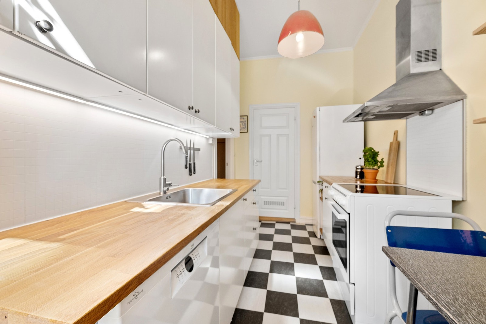 Kjøkkenet har overflater med malte slette fronter og benkeplate av heltré. Galleribilde