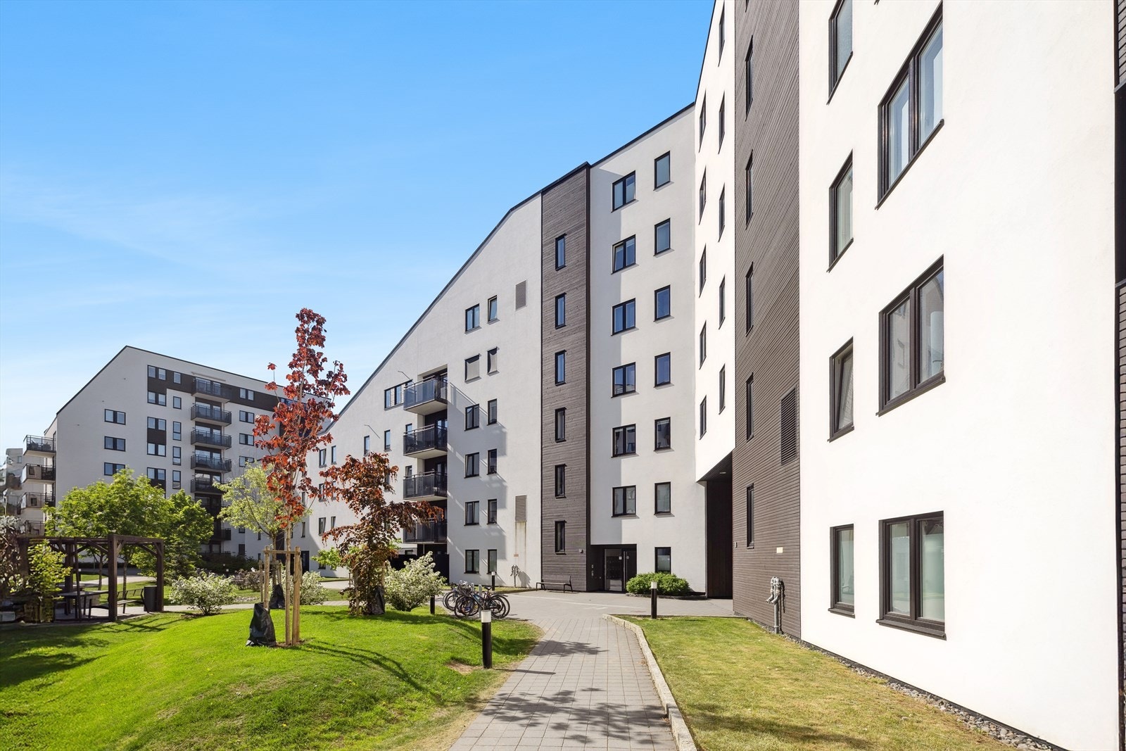 Fellesarealene består av grønne plener med sittegrupper, gangveier og sykkelparkering. Galleribilde