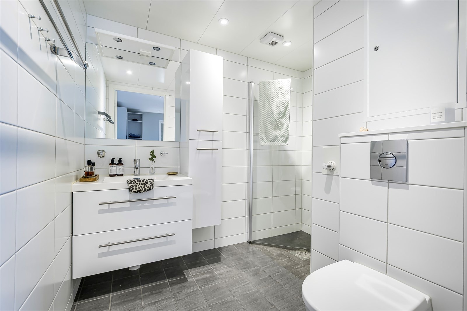 Badet er innredet med servant med innredning, sideskap, speil, toalett og dusjhjørne. Galleribilde