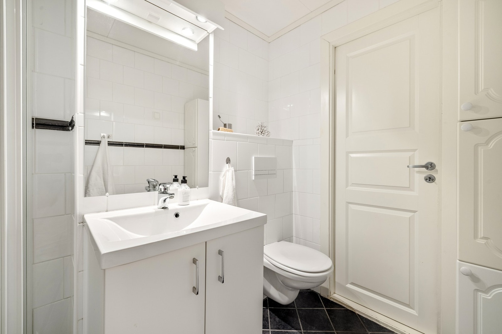Det er utstyrt med dusjhjørne med glassvegger, vegghengt toalett, baderomsinnredning og opplegg for vaskemaskin. Galleribilde