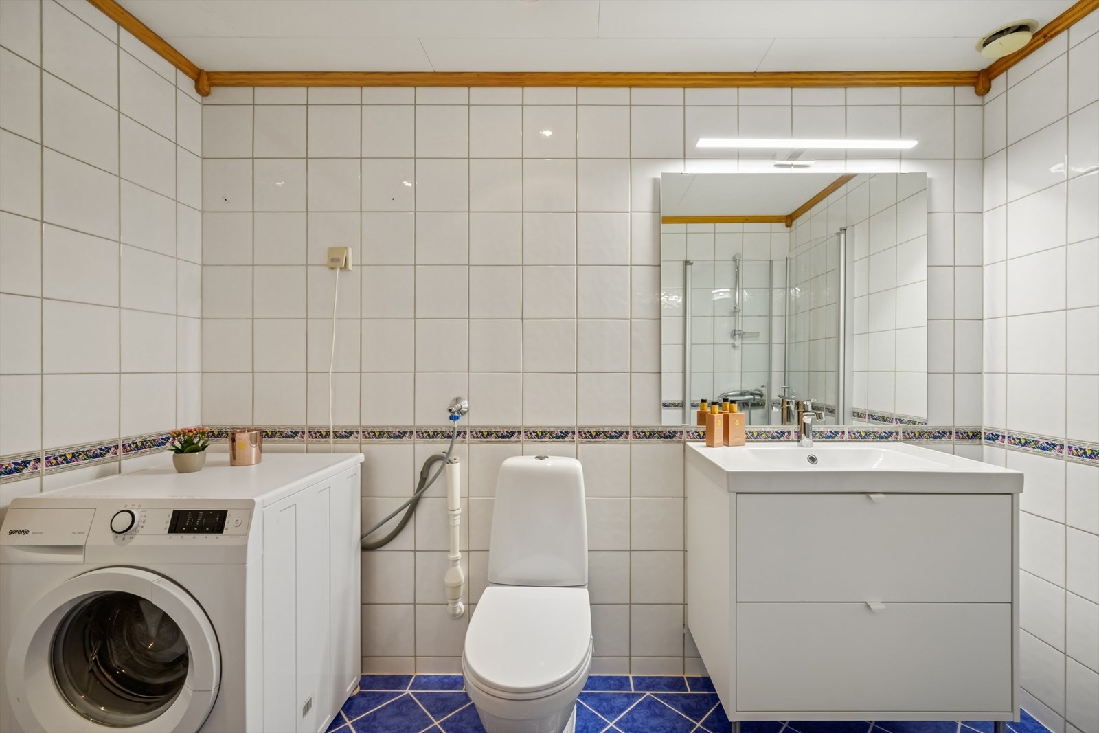 Badet har en praktisk og funksjonell utforming med toalett, servant med speil og belysning, samt dusjløsning med glassvegger i hjørne. Galleribilde