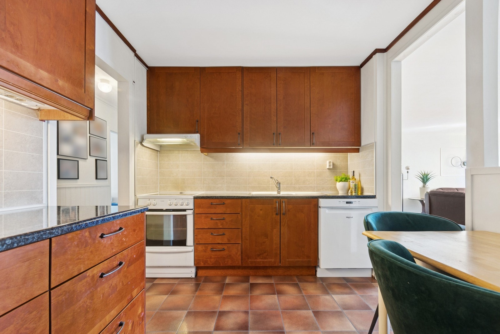 Kjøkkeninnredning med fronter i tonet bjørk, godt utstyrt med benkeplater og takhøye overskap som gir rikelig med oppbevaringsplass. Galleribilde