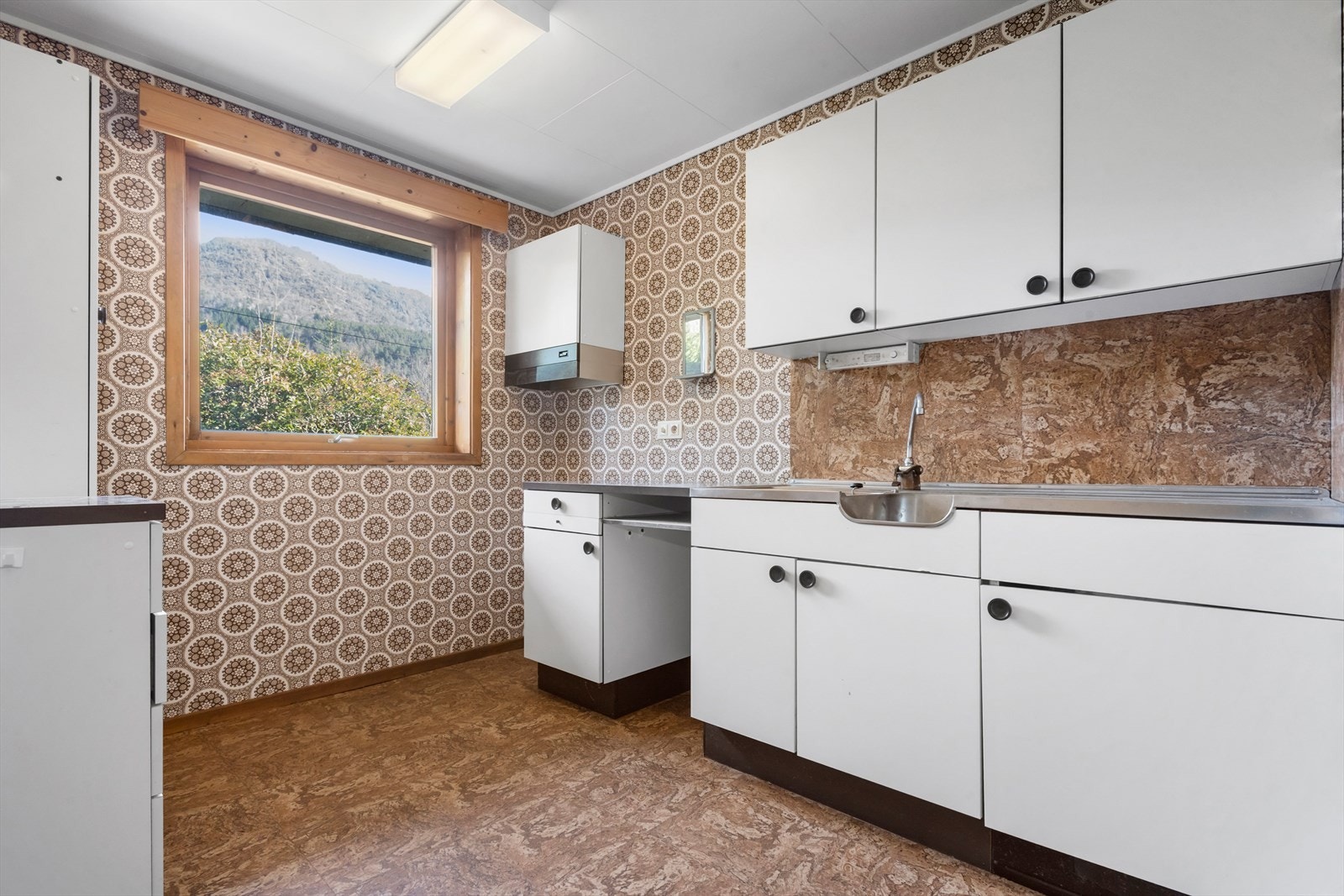 Kjøkken i underetasje. Innredning fra byggeår med hvite slette fronter. Galleribilde