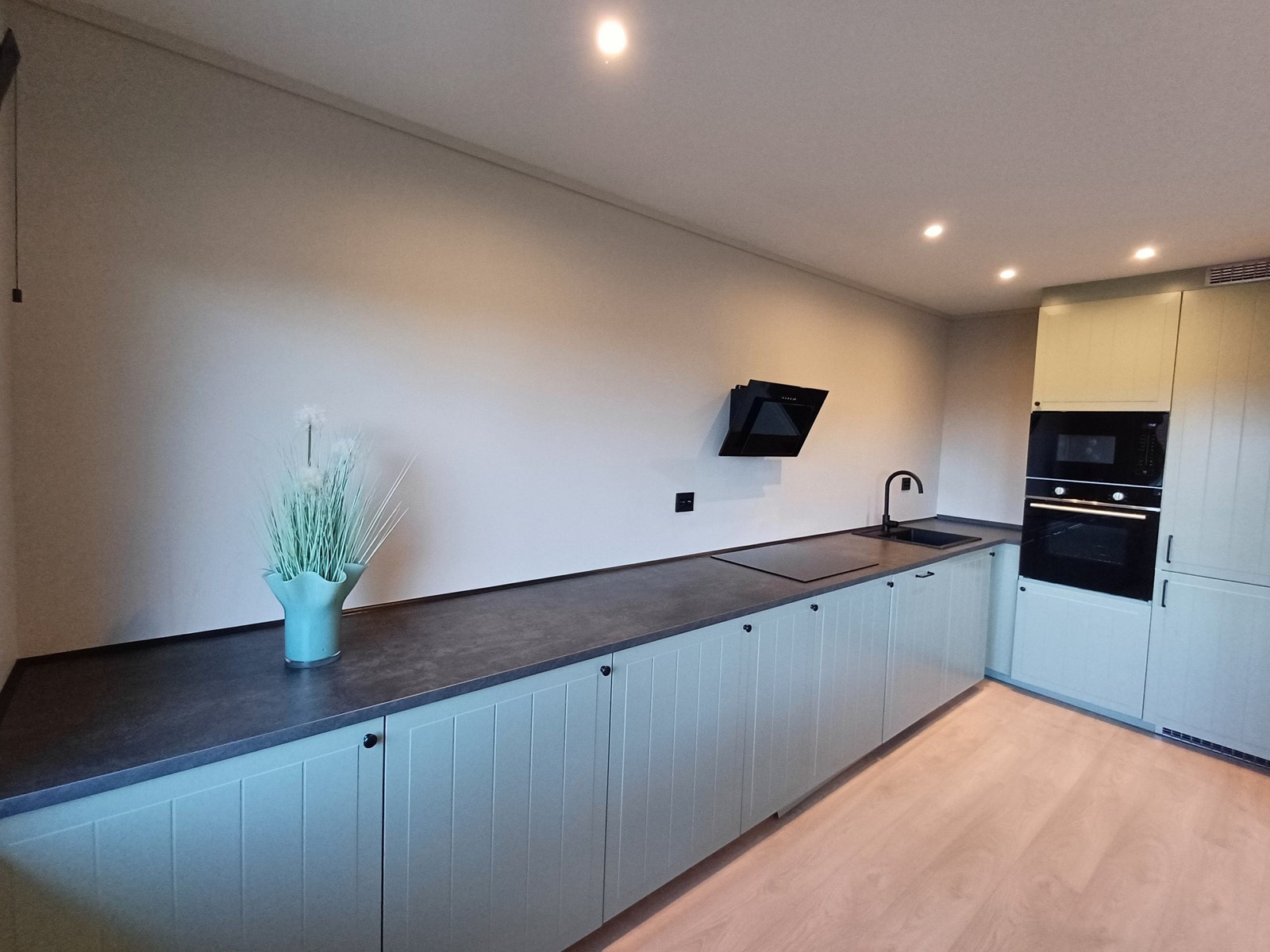 Lang kjøkkenbenk med masse skap og benkplass. Innebygde hvitevarer. Galleribilde