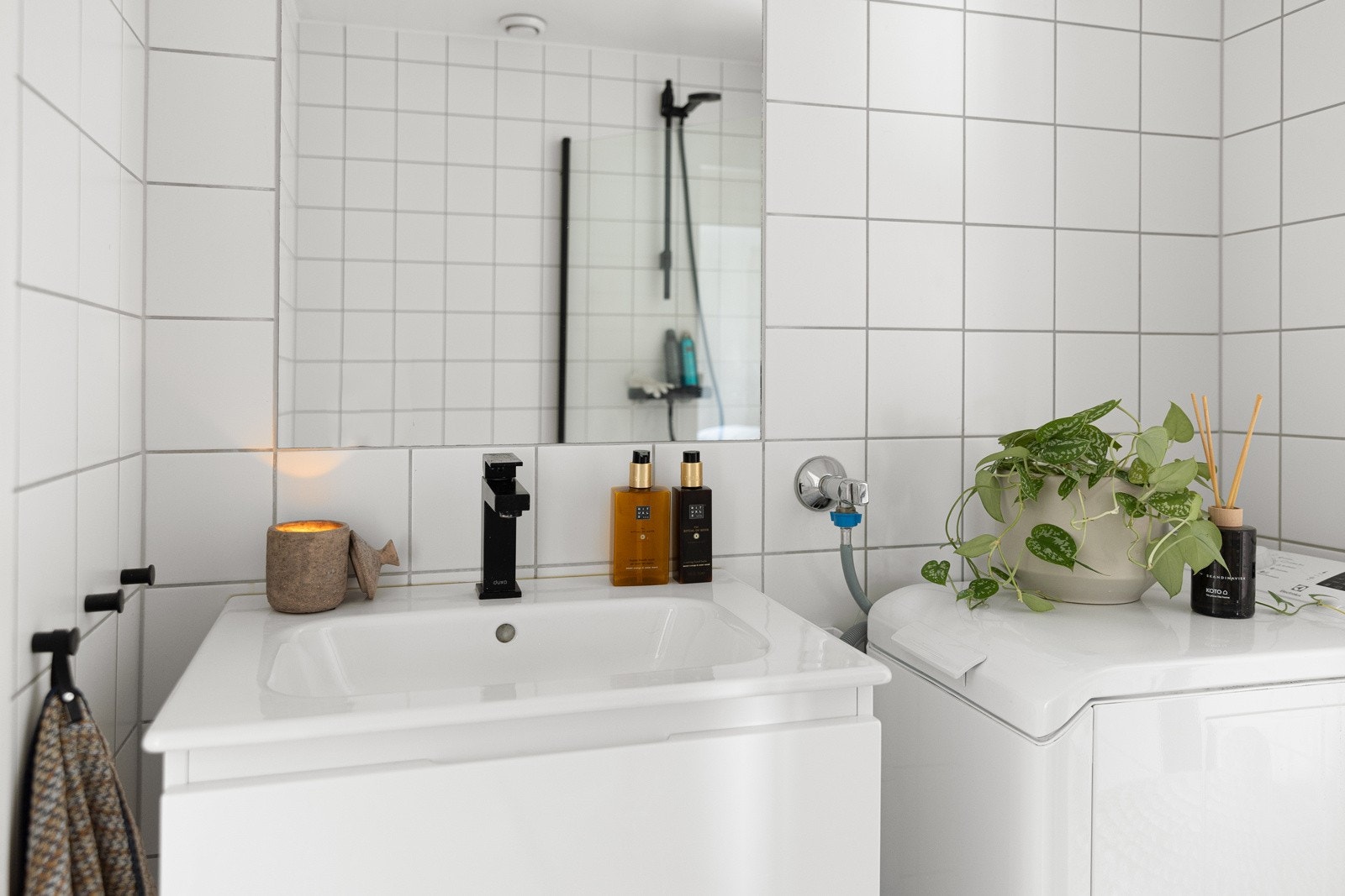 Stilren og moderne baderomsinnredning med skuffer og heldekkende servant med sort armatur. Galleribilde