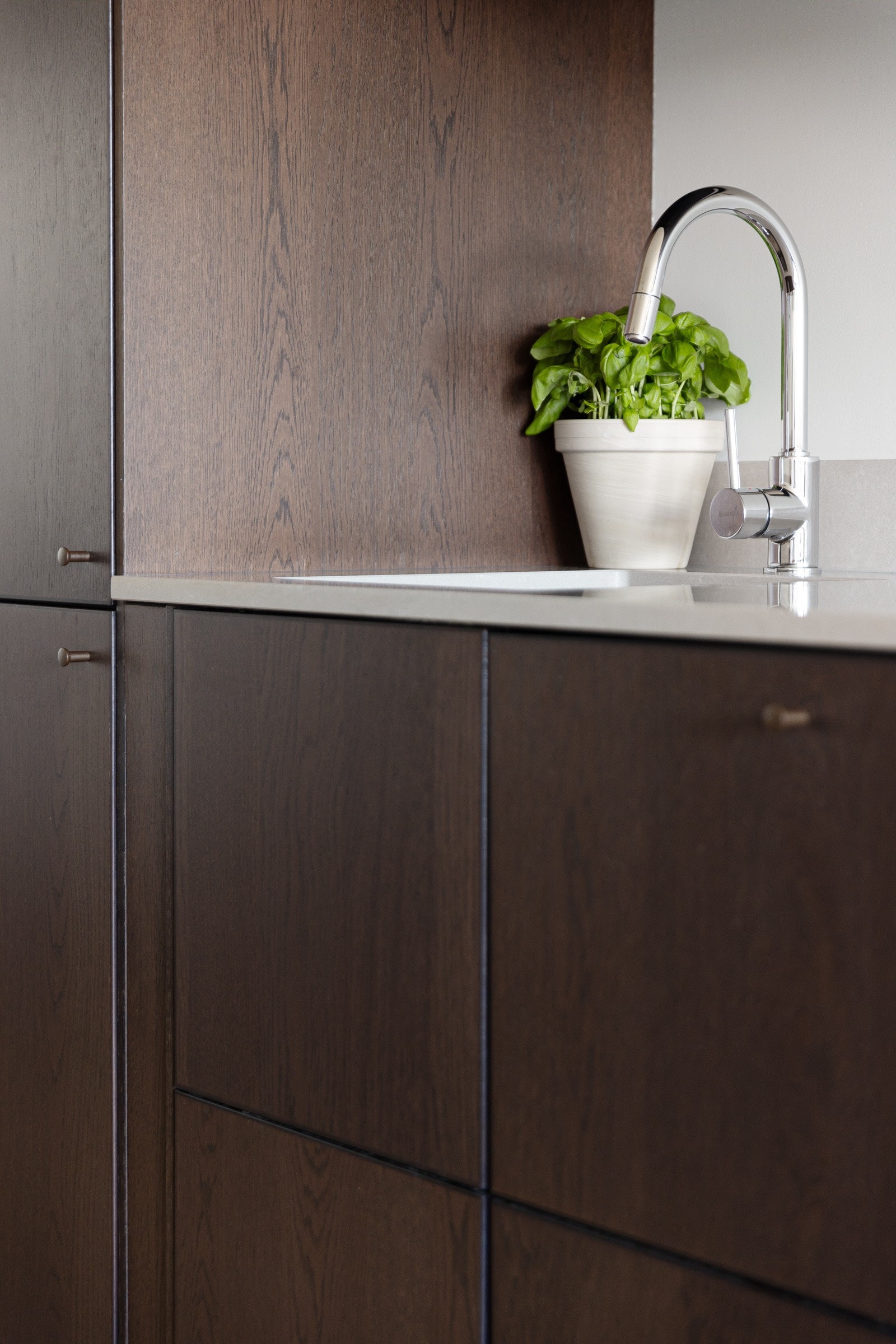 Innredningen har glatte fronter i mørk trestruktur og påkostet benkeplate i kompositt med underlimt oppvaskkum. Galleribilde