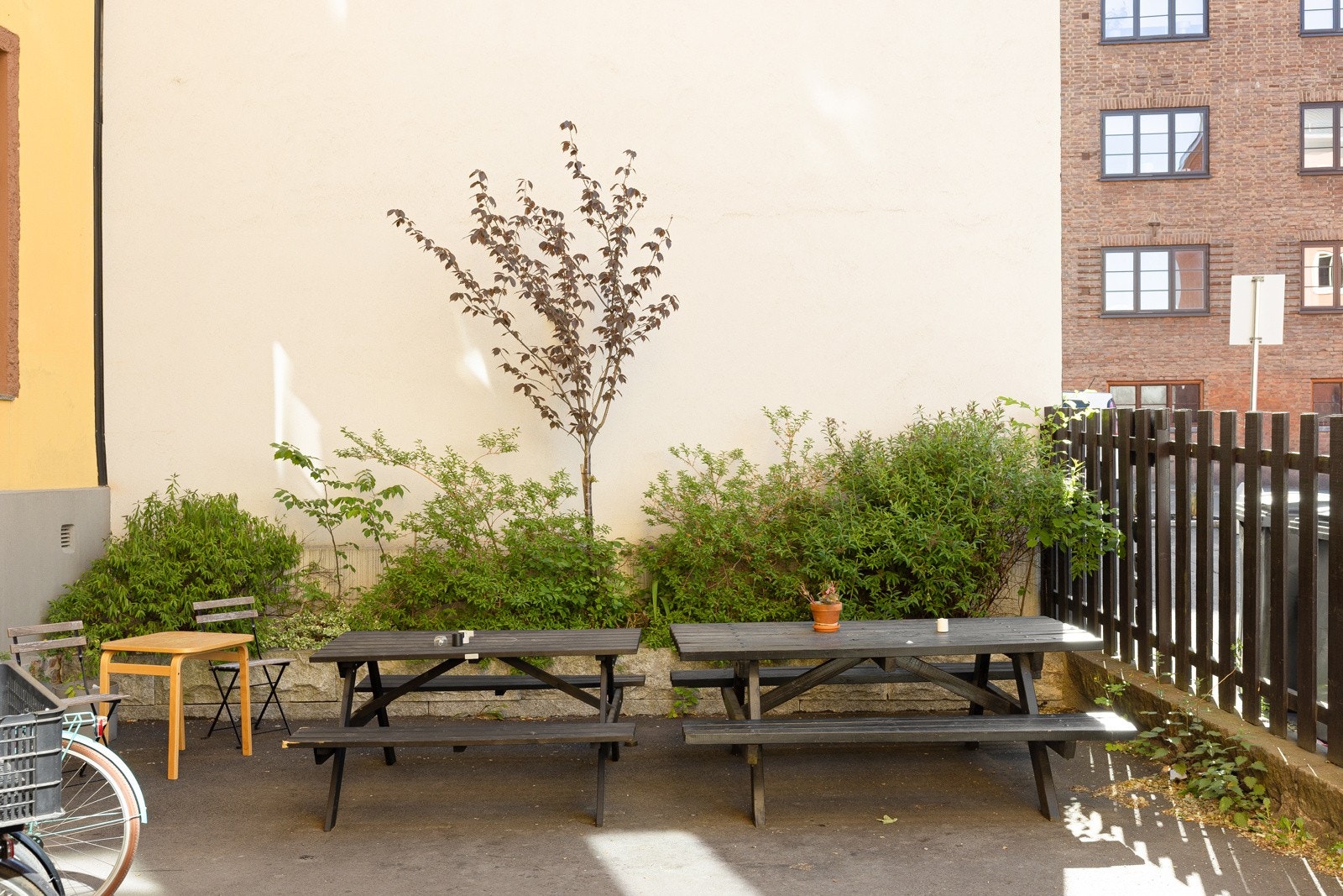 Stensatt felles gårdsrom med sittegruppe, avgrenset med gjerde mot gate. Flott sommerbakgård med sittegrupper Galleribilde