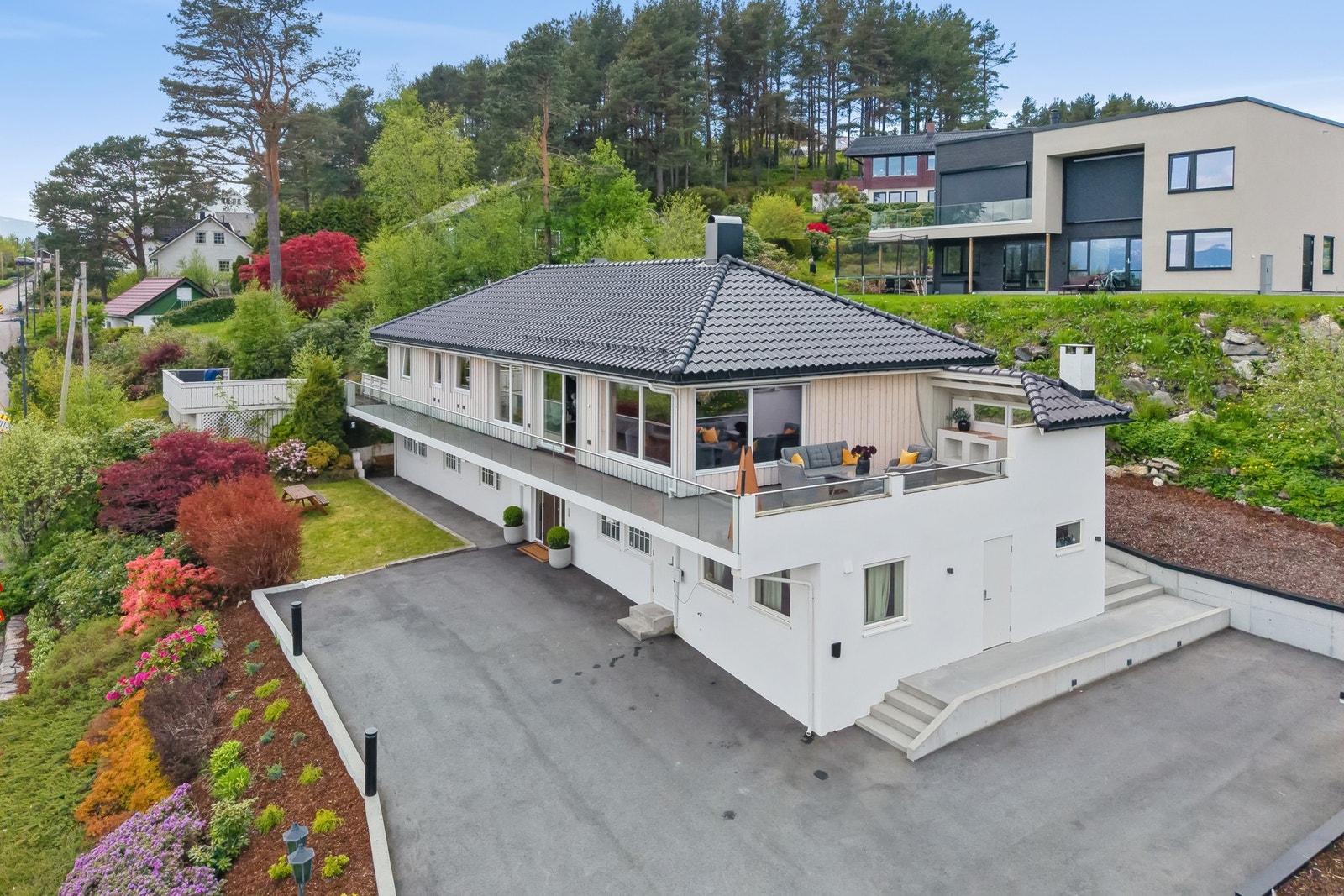 Eneboligen ligger på en stor og solrik tomt, flott opparbeidet med nylagt asfalt og støpte murer på gårdsplassen. Galleribilde