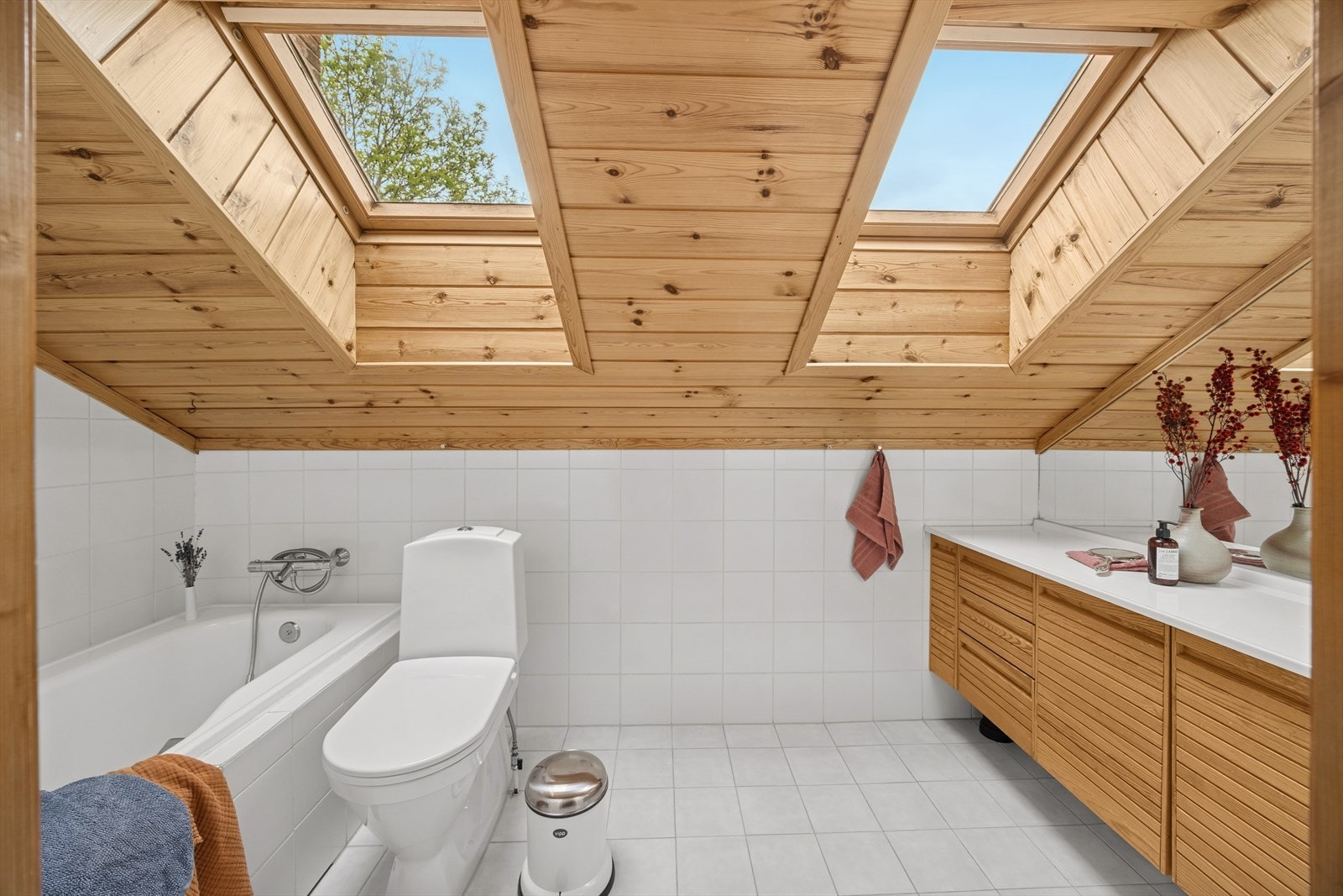 Badet i 2. etasje har flislagte overflater, servant, toalett og badekar under takvindu. Galleribilde