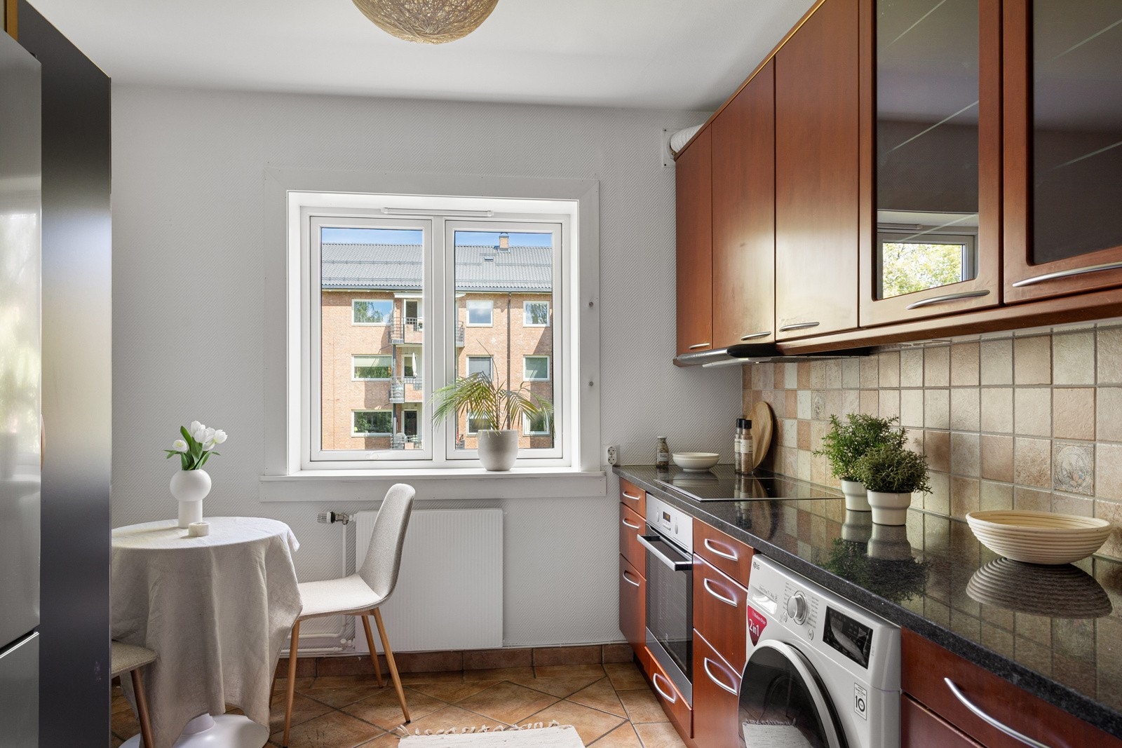 Separat kjøkken. Kjøkkeninnredning med finérte fronter, overskap og fliser på vegger Galleribilde