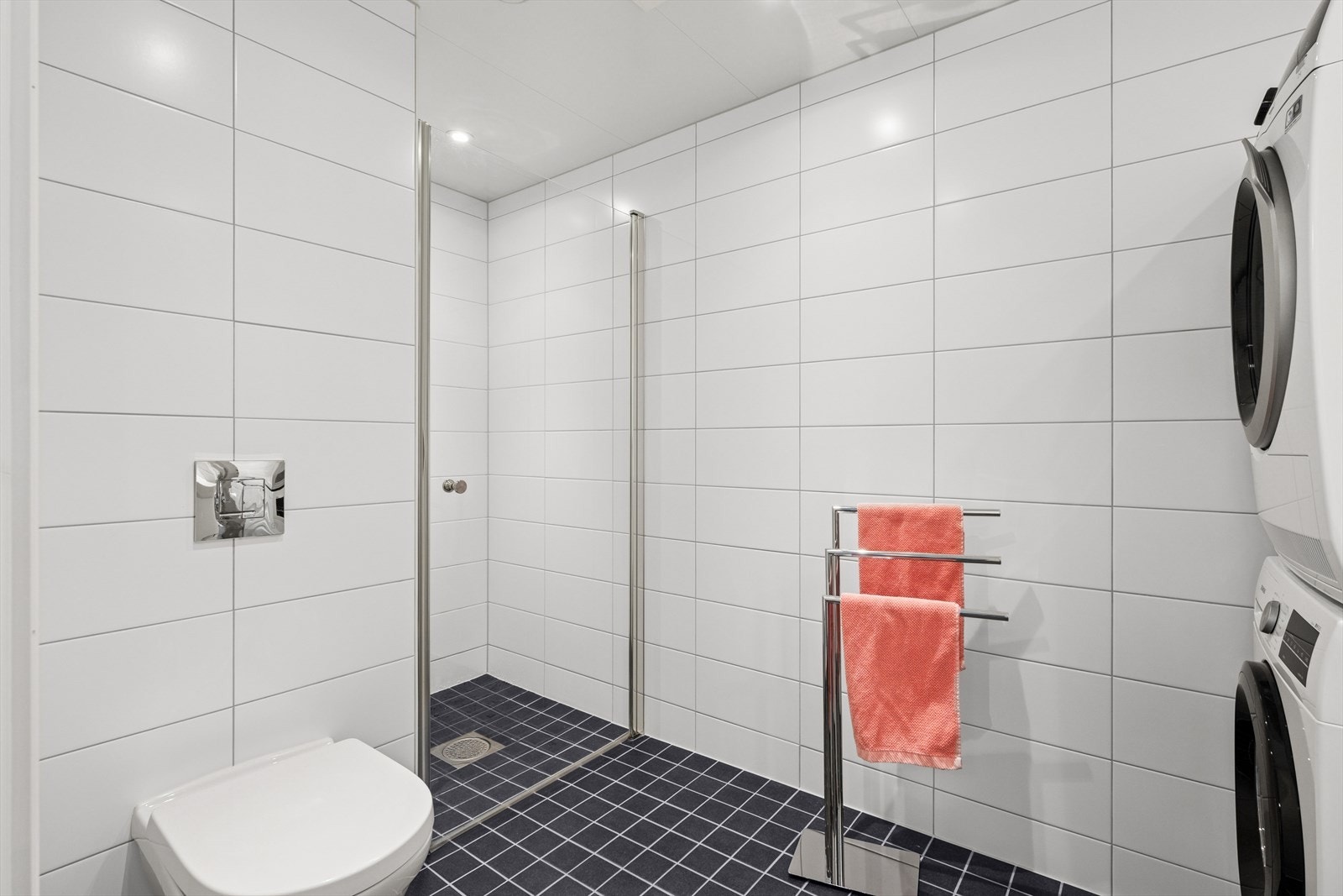 Det er montert baderomsinnredning med skuff og servant, vegghengt toalett, opplegg for vaskemaskin, plass til tørketrommel og en romslig dusjsone med glassdør. Galleribilde
