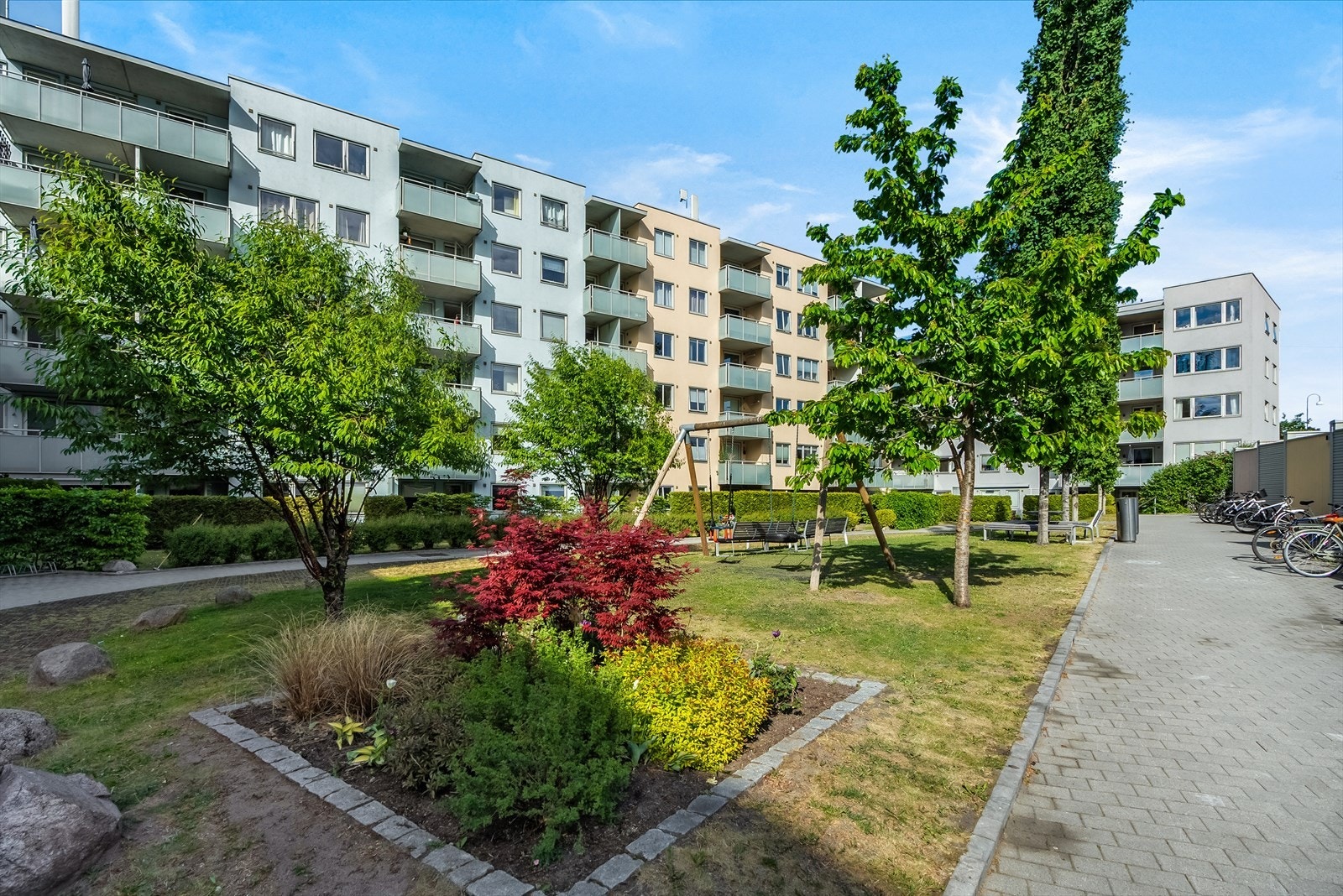 Flott felles gårdsplass, pent opparbeidet med grøntarealer bestående av plen og prydbusker. Galleribilde