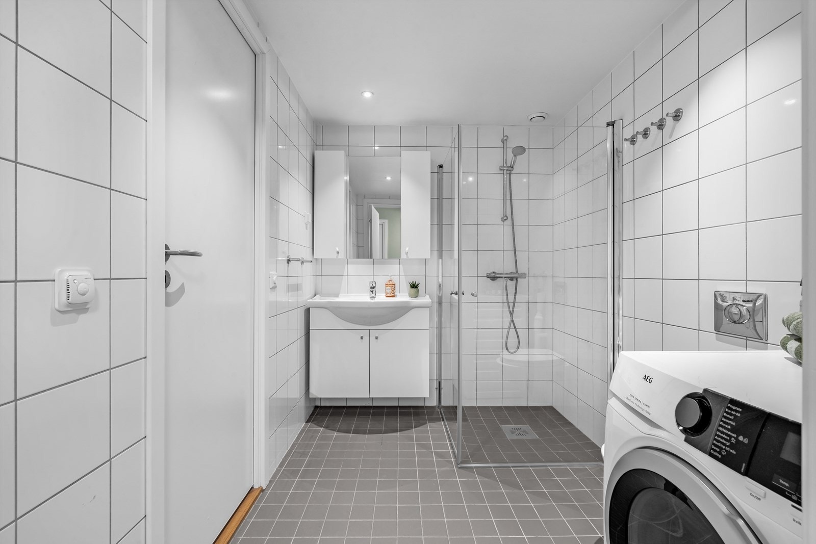 Et romslig og pent baderom med elektrisk gulvvarme og mekanisk avtrekk. Badet er innredet med vegghengt klosett, servant med innredning og dusjhjørne med svingbare glassdører. Galleribilde