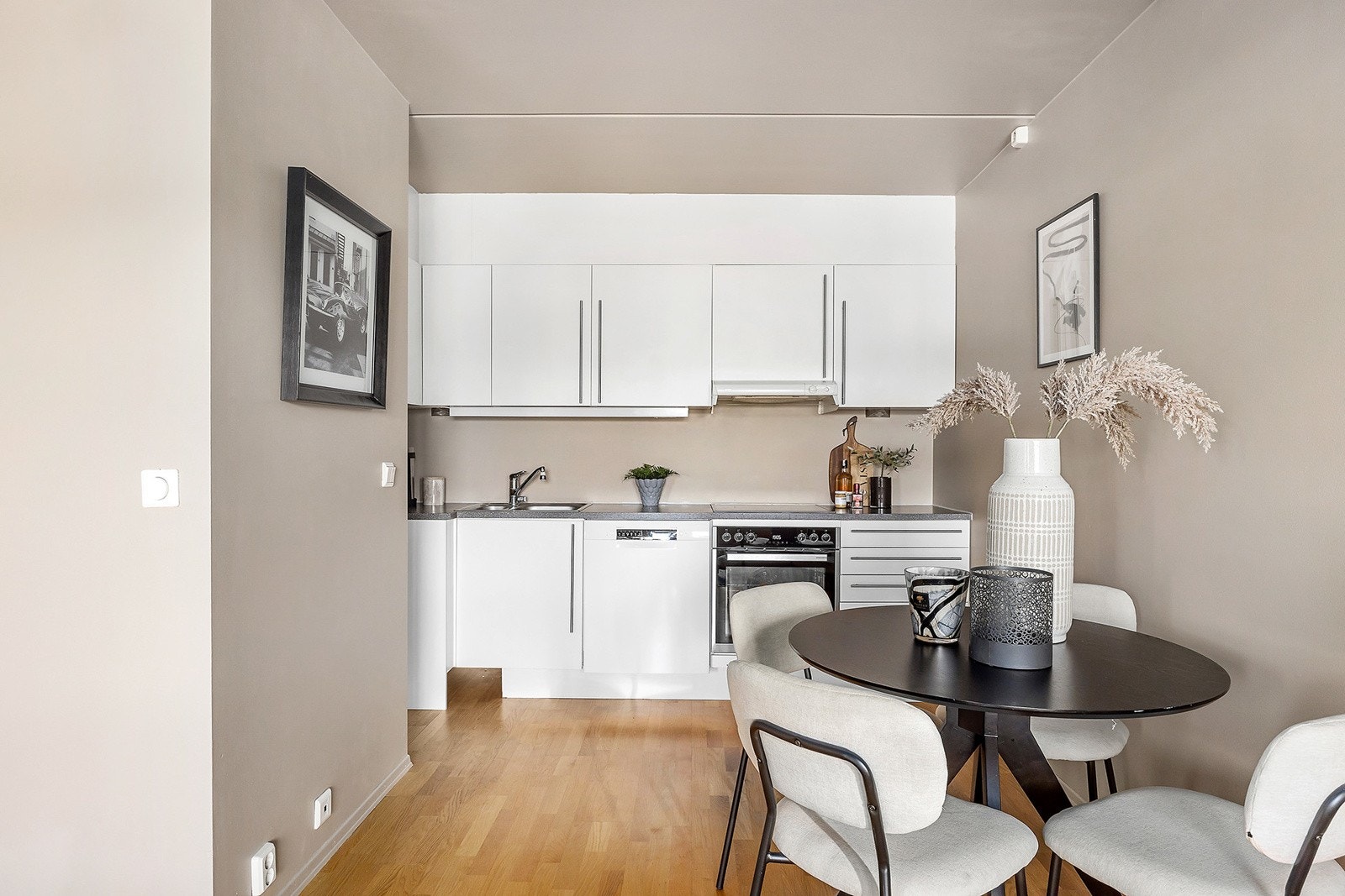 Kjøkkeninnredning med glatte laminerte skapfronter, laminat benkeplate, ventilator og innfelte hvitevarer som koketopp, stekeovn (Ny 2022), frittstående oppvaskmaskin (Ny 2023), kjøl/- fryseskap. Galleribilde