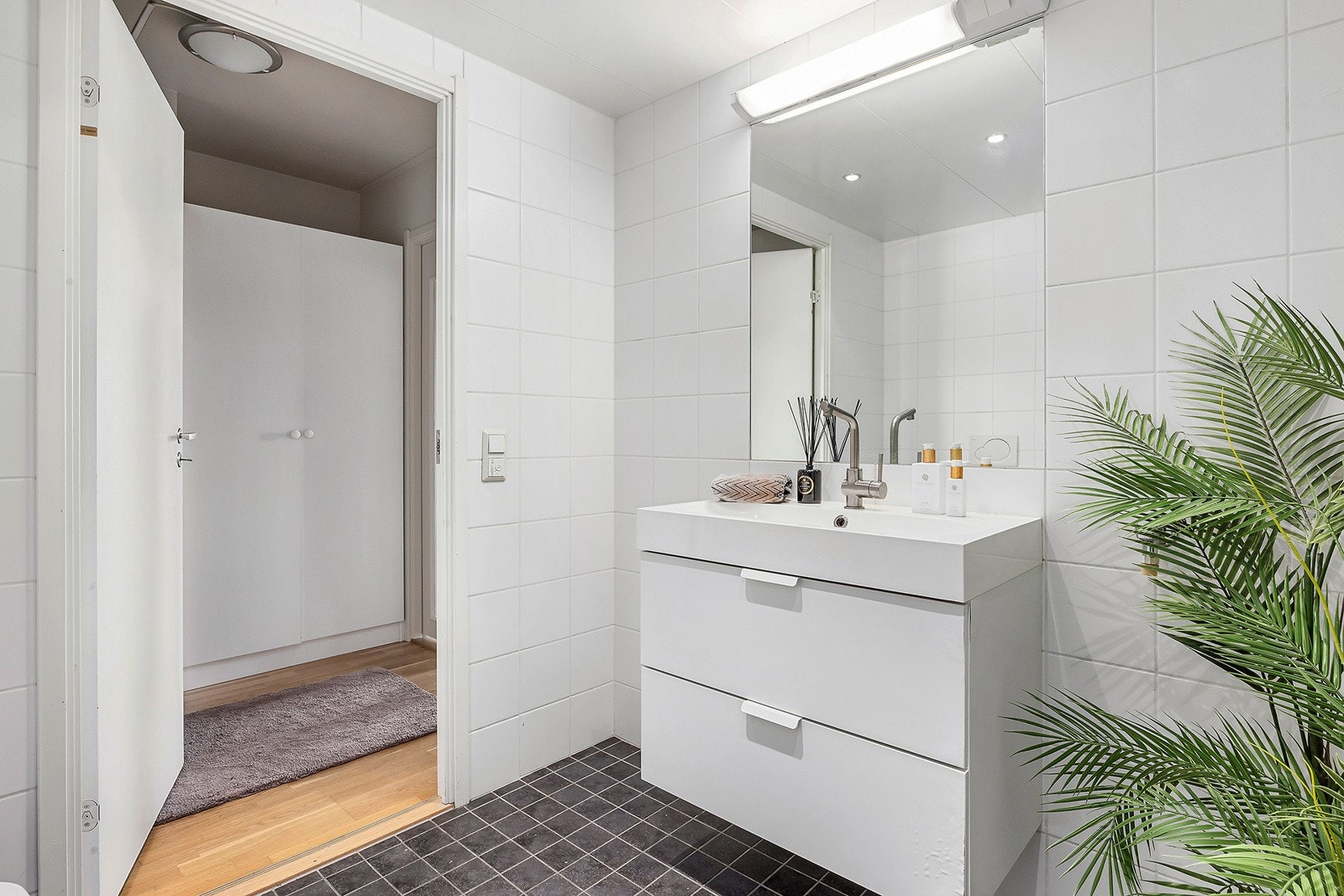 Baderomsinnredningen er bestående av servant med skuffeseksjon, innfliset speil, vegghengt klosett, dusjhjørne med svingbare glassdører og opplegg for vaskemaskin. Galleribilde